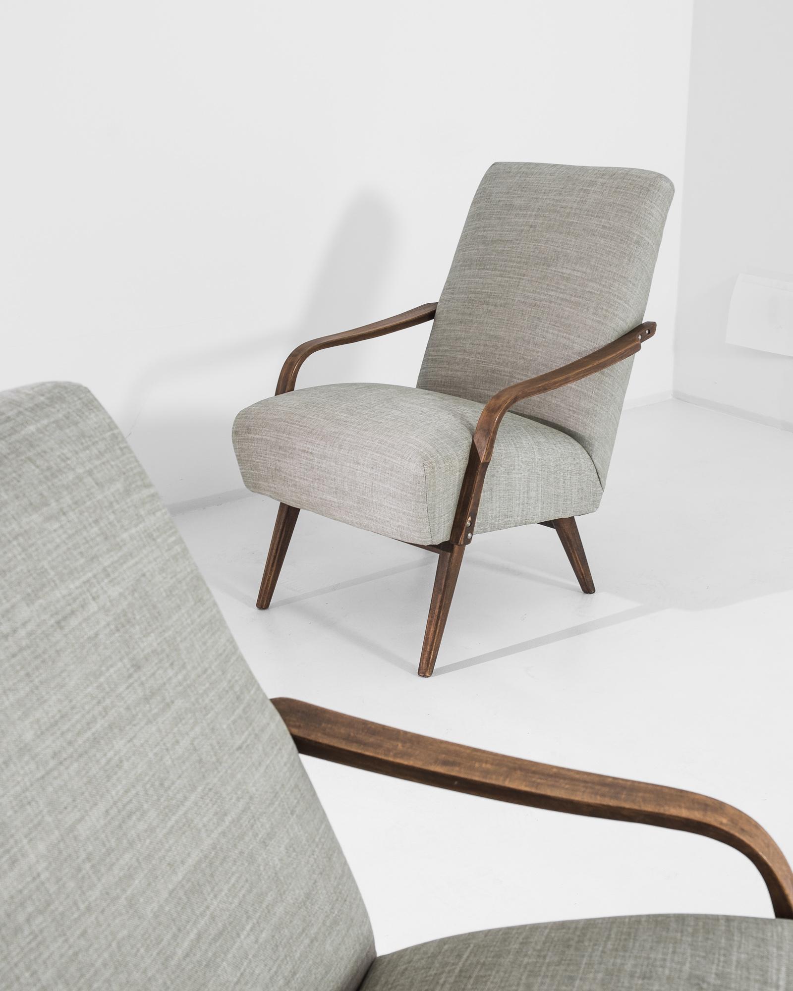 A pair of armchairs produced in the former Czechoslovakia. This 1960s design is re-upholstered in an updated ecru fabric, the neutral tone was chosen to compliment the natural brown of the hardwood frame. Comfortable angles and clean lines, the