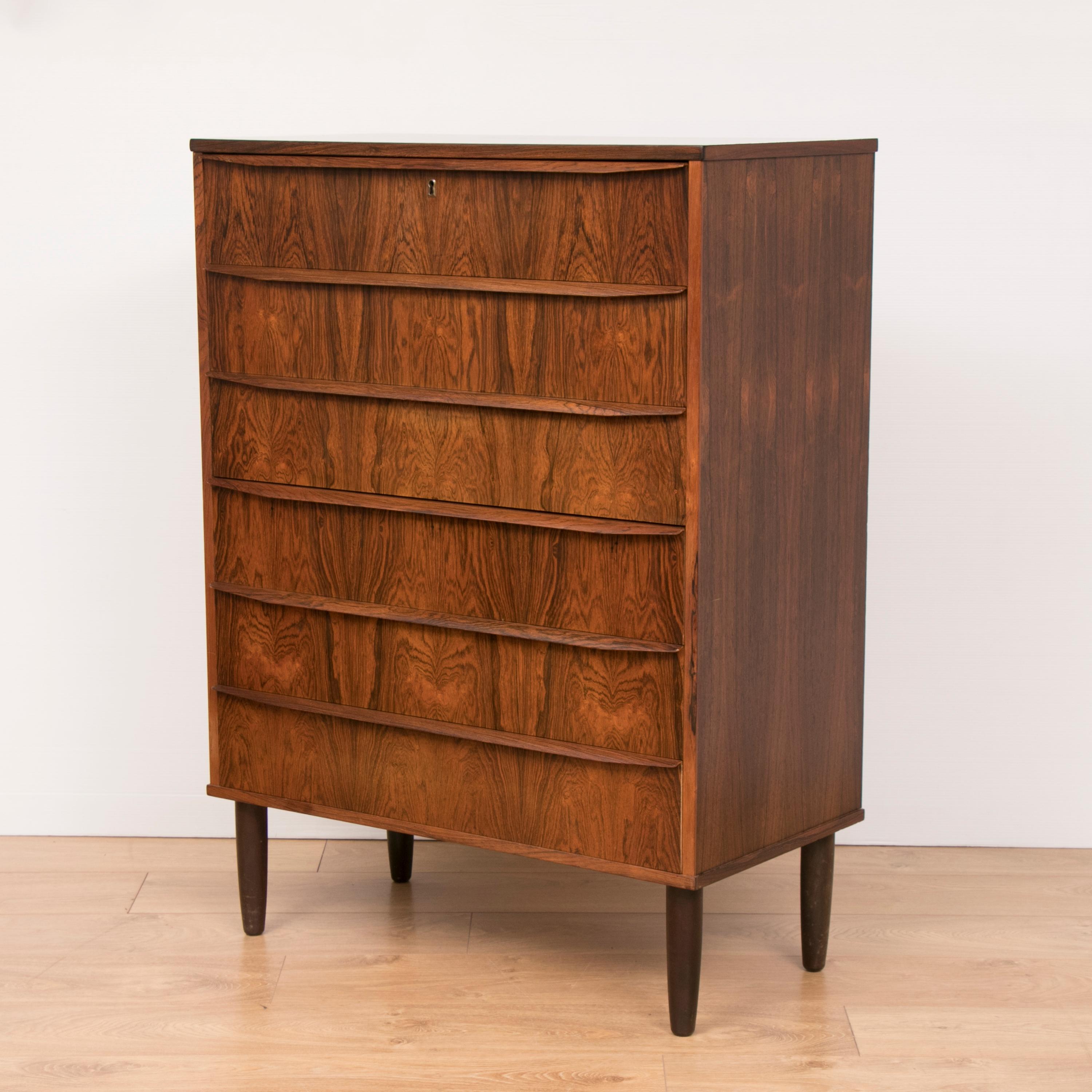 1960s Danish midcentury Brazilian rosewood chest of six-drawers with a matching grain pattern on the front of each drawer. Long lip handles run along the whole length of each drawer. The top drawer is lockable with a brass feature lock and key. The