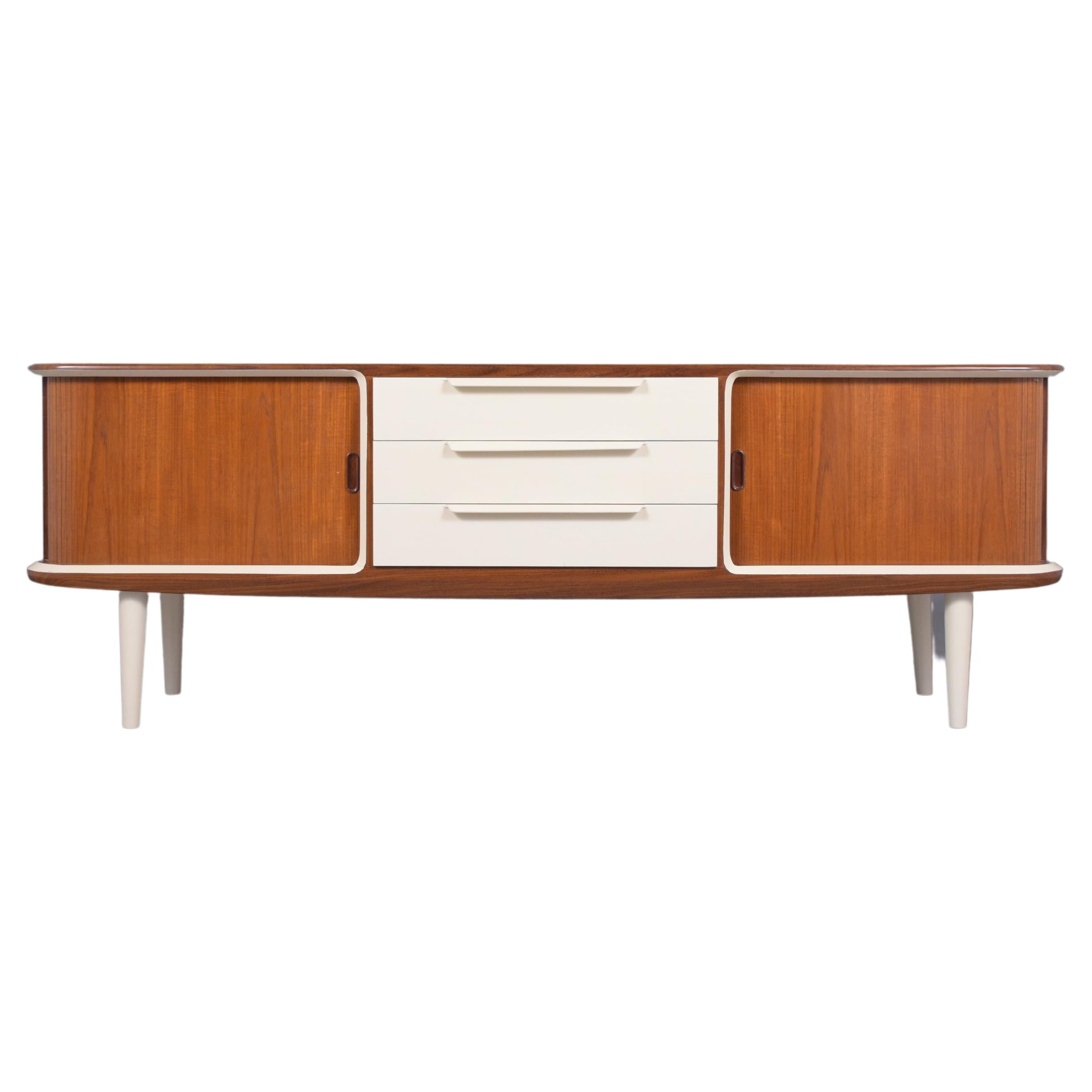 An extraordinary 1960s modern danish credenza is crafted out of teakwood and has been fully restored by our team of in-house craftsmen. The piece has been stained walnut with a newly lacquered finish and features beige accent color moldings