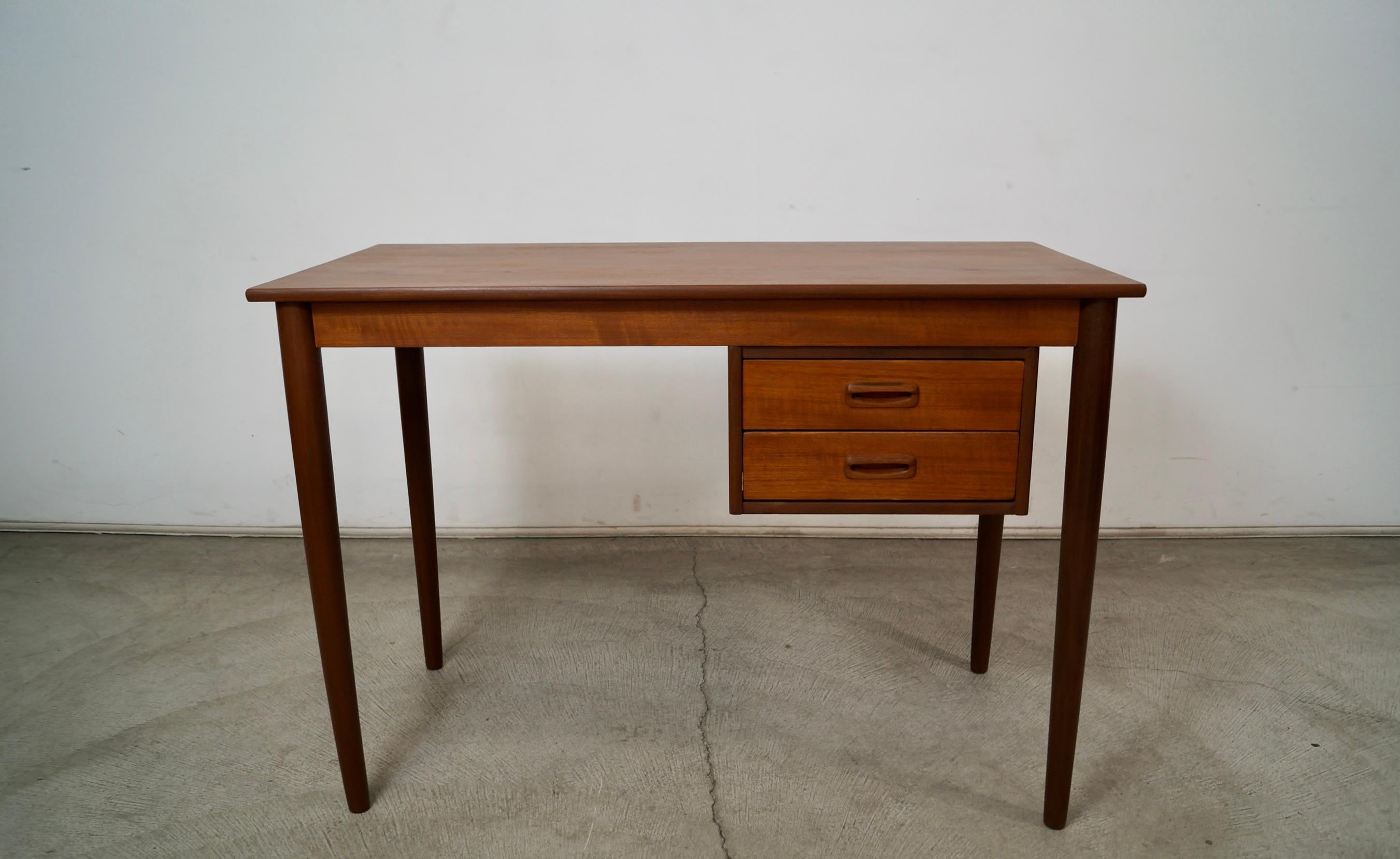 Scrivania originale vintage del Midcentury Modern in vendita. Prodotto negli anni '60 e realizzato in Danimarca. Realizzato in teak, è stato rifinito. Ha due cassetti e le maniglie scolpite in teak massiccio. Ha delle bellissime venature di teak e