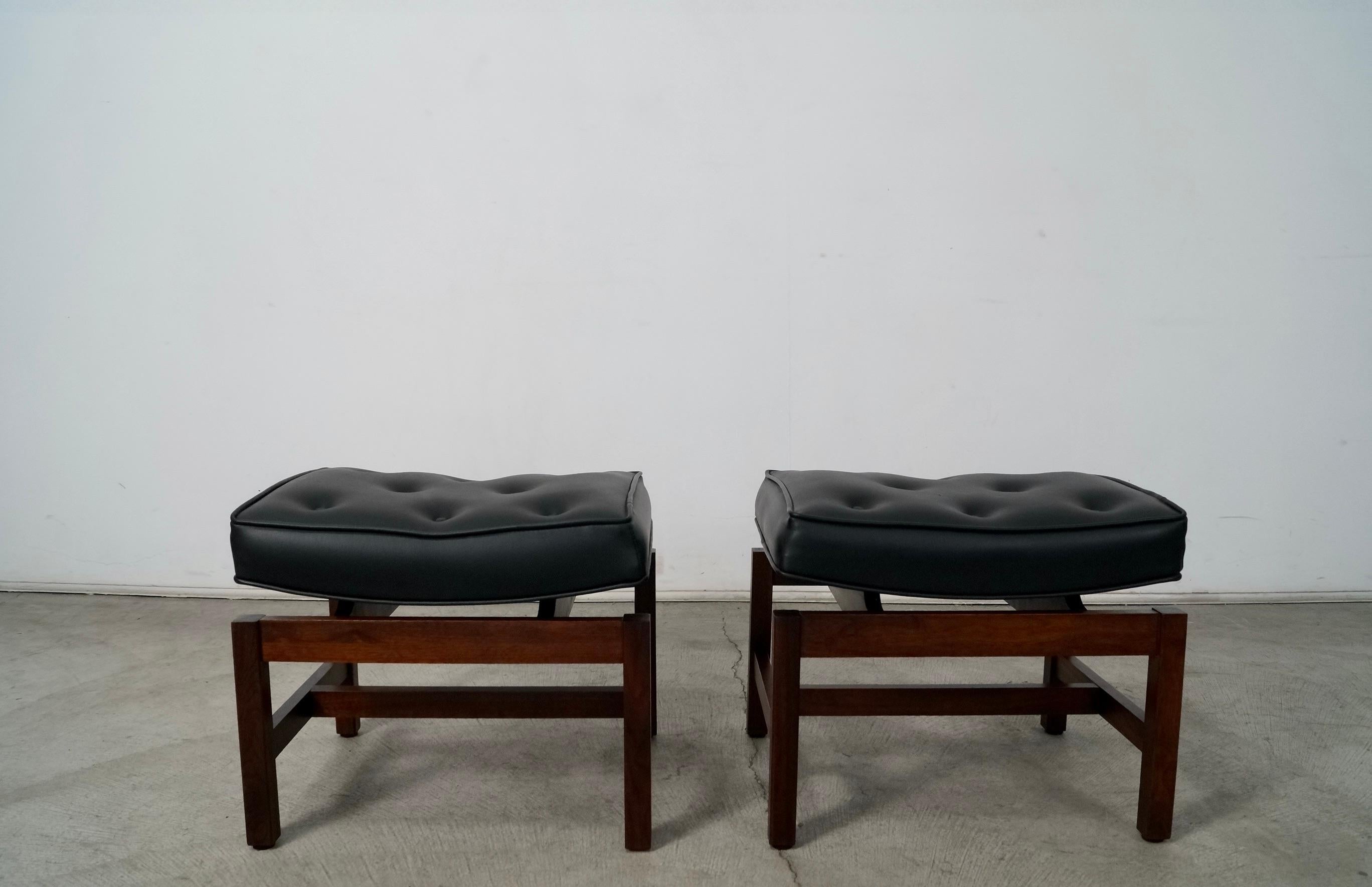 Pair of original Midcentury Danish Modern floating benches for sale. They were designed by Jens Risom, and are in excellent condition. They have a solid walnut sculptural base with a floating top. The original upholstery is a black naugahyde faux