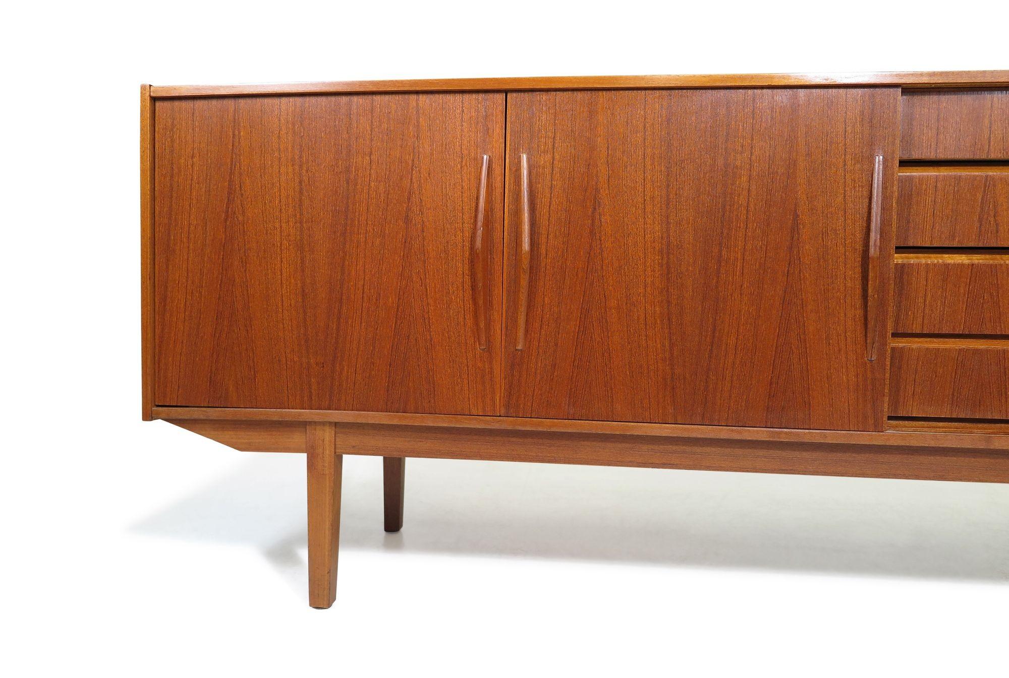 1960s Danish teak credenza crafted with three sliding doors and series of four drawers, each adorned with angled triangular pulls, raised on tapered legs. The interior is made of cuban mahogany with adjustable shelves. Restored in a natural oil