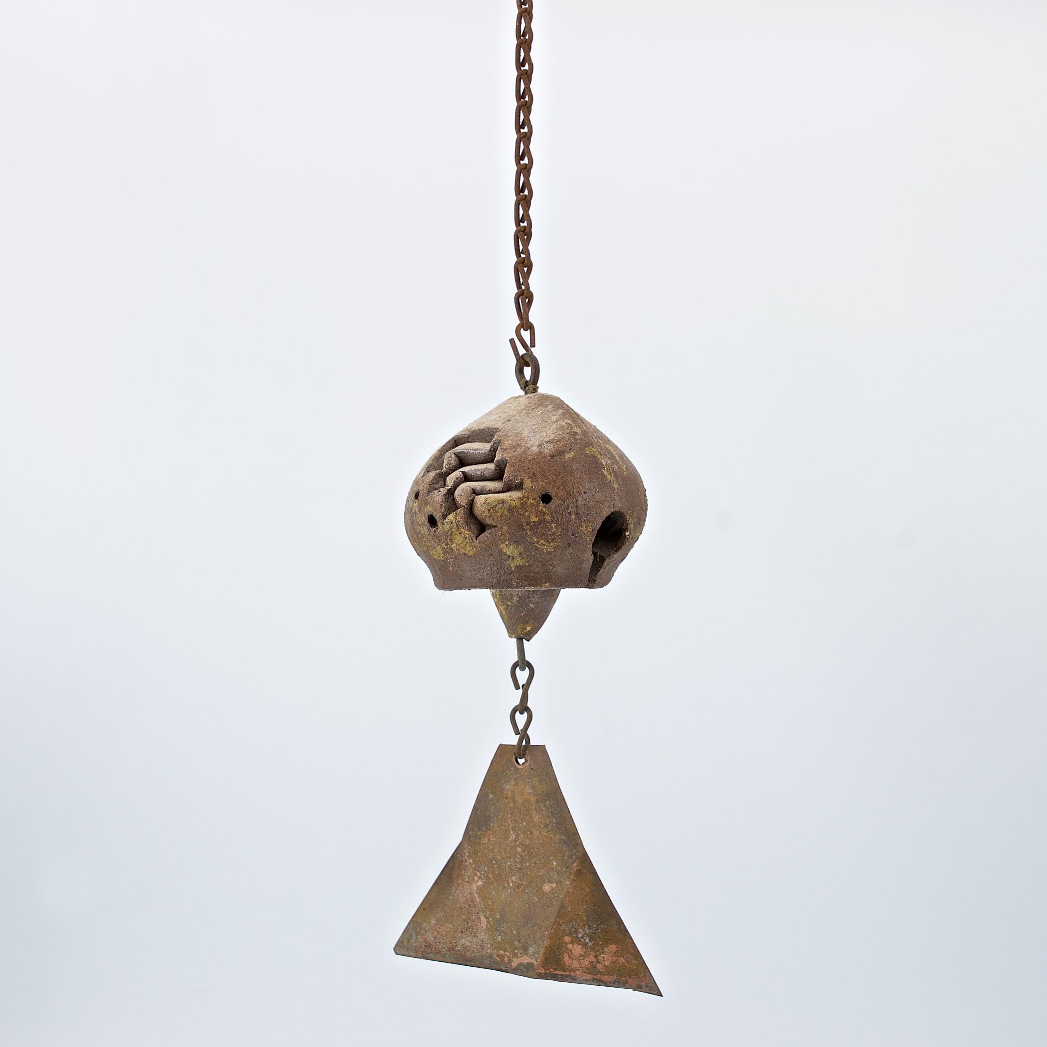Clay chime with incised abstract designs, with clay clapper and copper fin. Designed by Paolo Soleri and hand-crafted at Arcosanti, c.1960. No discernible cracks, hairlines, or chips. With the Arcosanti cypher mark. Bell is 3
