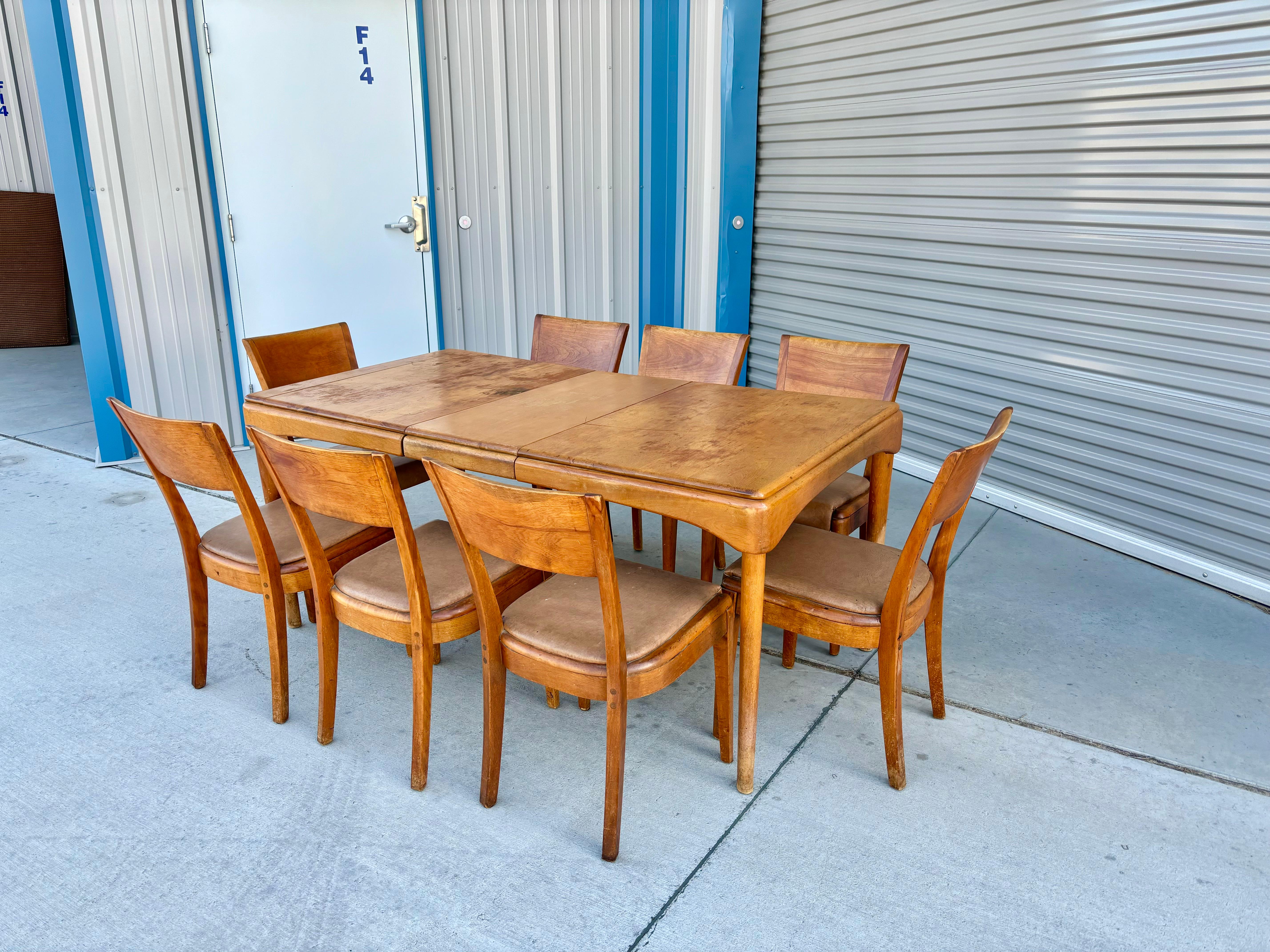 This mid-century maple dining room set was designed and manufactured by Heywood Wakefield in the United States circa the 1960s. This unique set features eight dining chairs made in sturdy maple frames and a captivating brown vinyl upholstery that