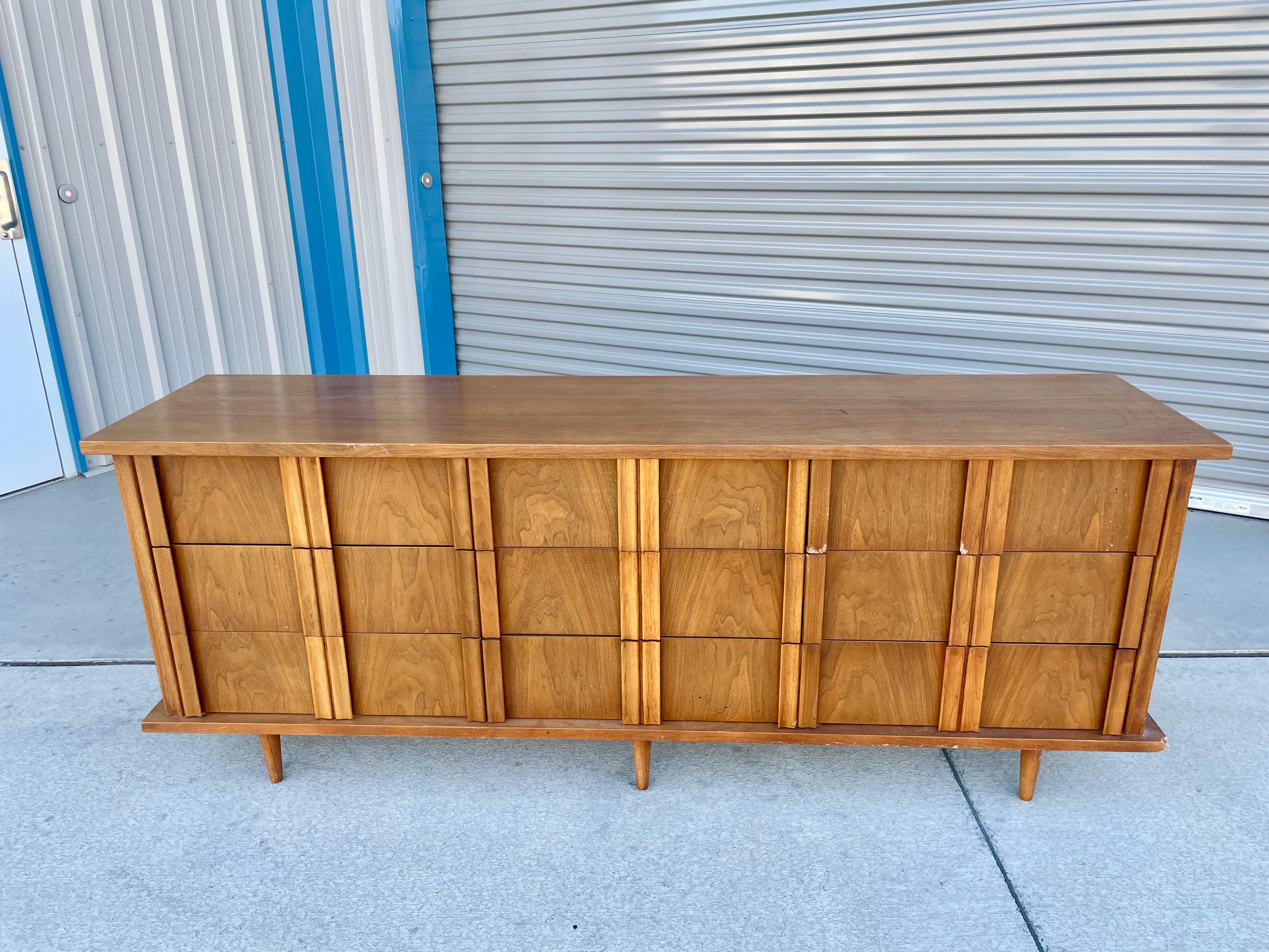 Mid-century walnut dresser designed and manufactured by American of Martinville circa 1960s. This beautiful dresser features a walnut frame with nine pull-out drawers. Each drawer comes with a walnut sculptured handle, giving it a unique design to