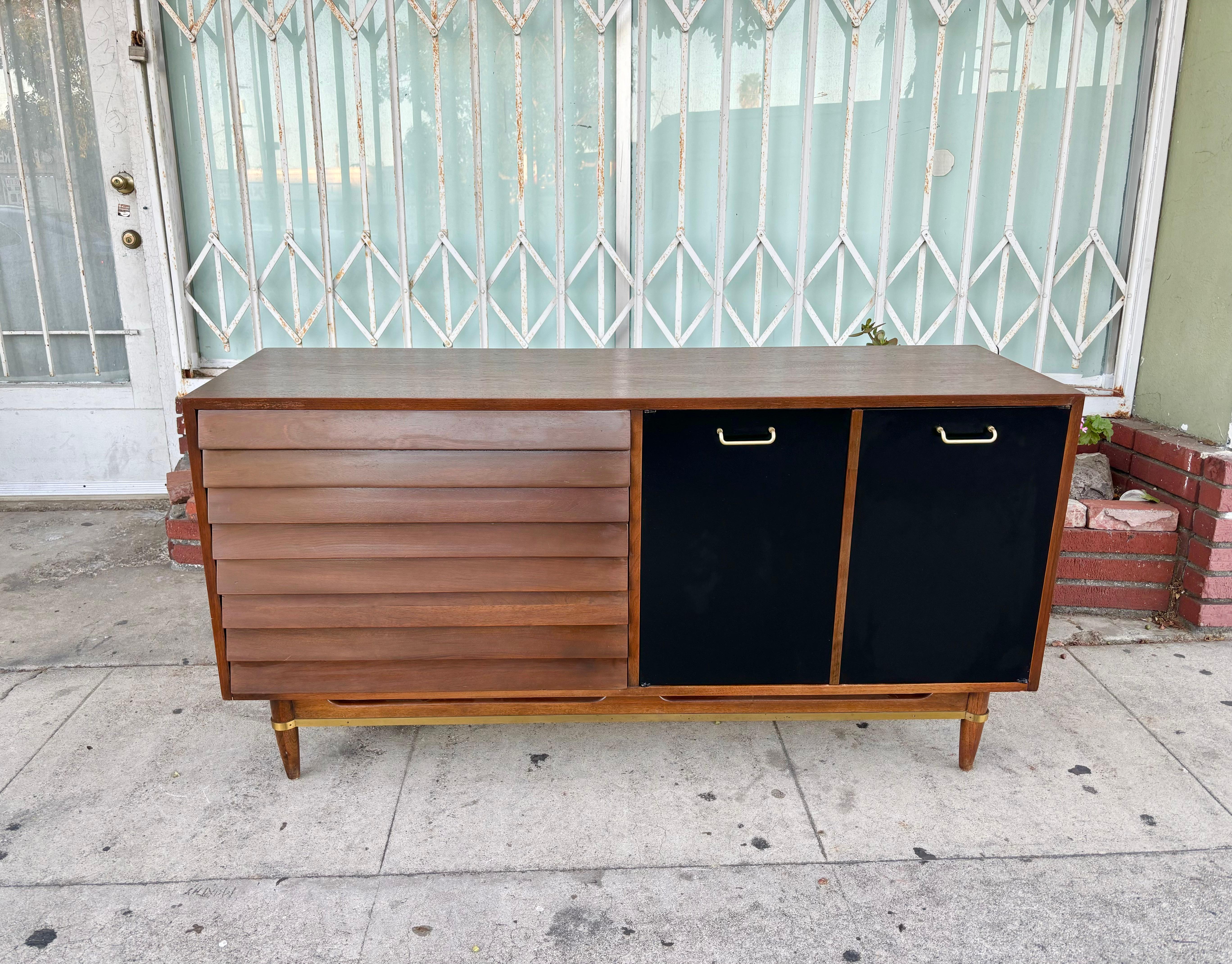 Mid-century walnut dresser designed by Merton L. Gershun and manufactured by American of Martinville. This dresser features a walnut frame with three spacious dovetail drawers on the left side, while the right side features two elegant black doors