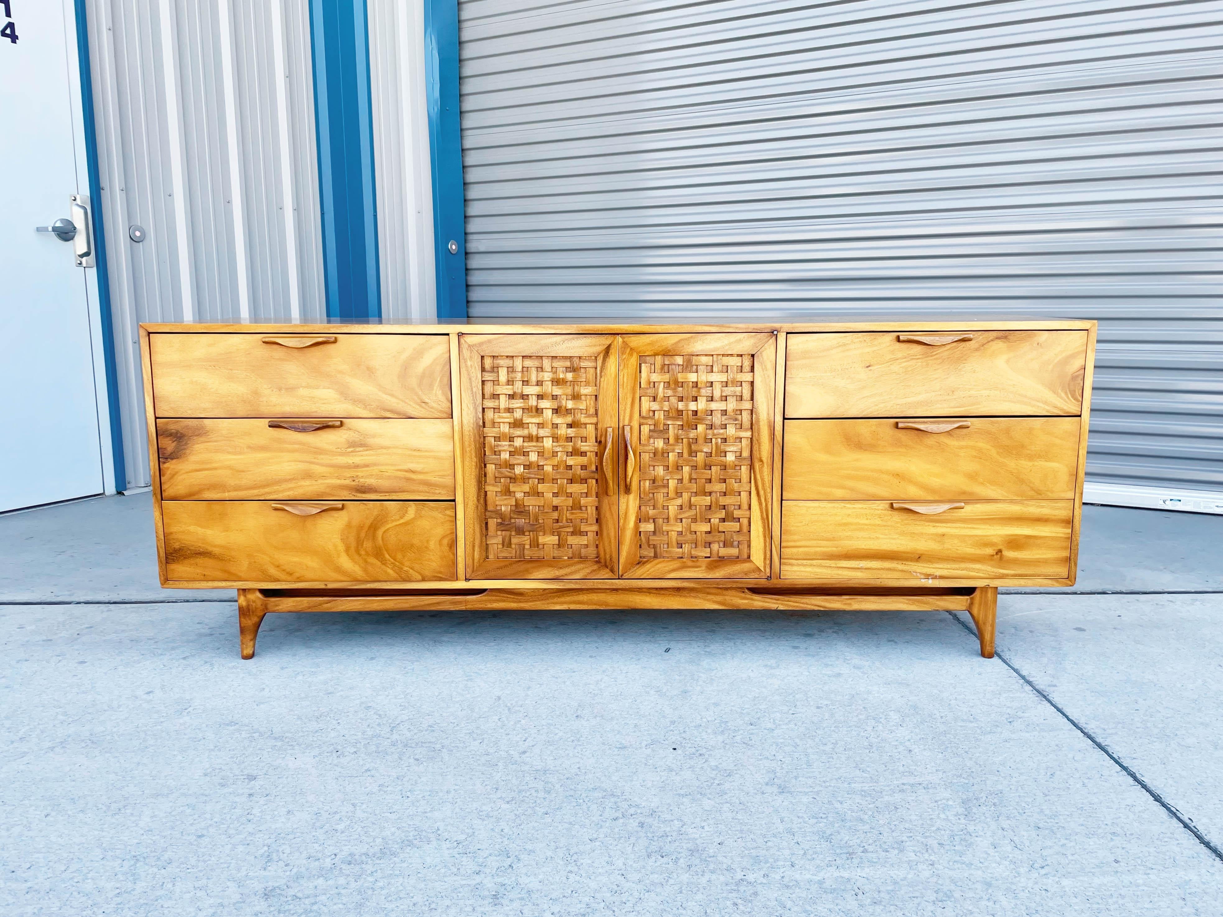 This mid-century modern walnut credenza was expertly designed and made in the United States in the 1980s. Inspired by Lane furniture, this striking piece showcases a stunning walnut frame that will elevate the style of any room. With six spacious