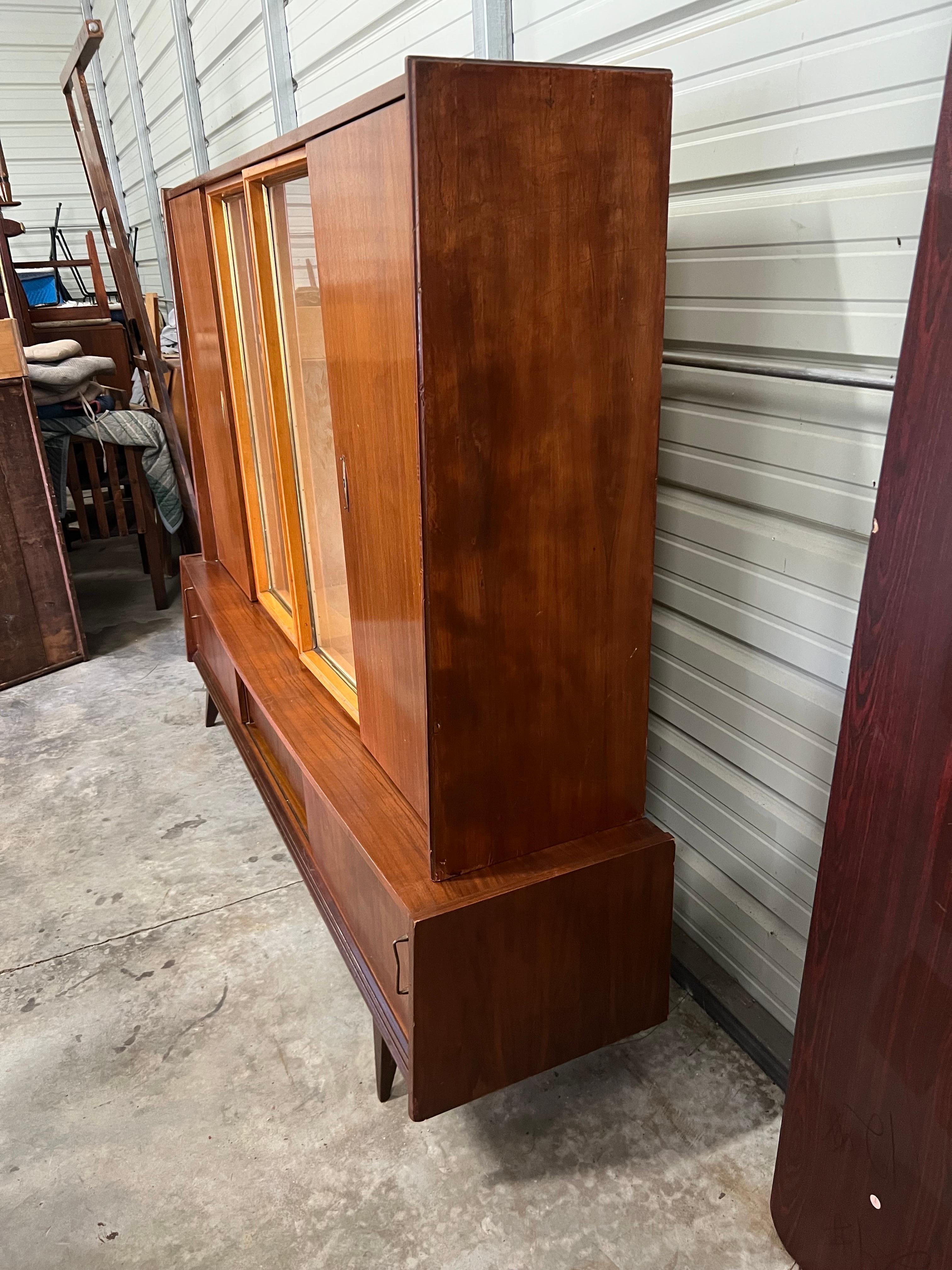 Plenty of storage with this piece. This unit comes in two pieces; one larger display unit set onto a low profile, EXTRA long credenza. 
Two large, lock and key cabinets I on each side, each having adjustable shelves. A double glass door and glass