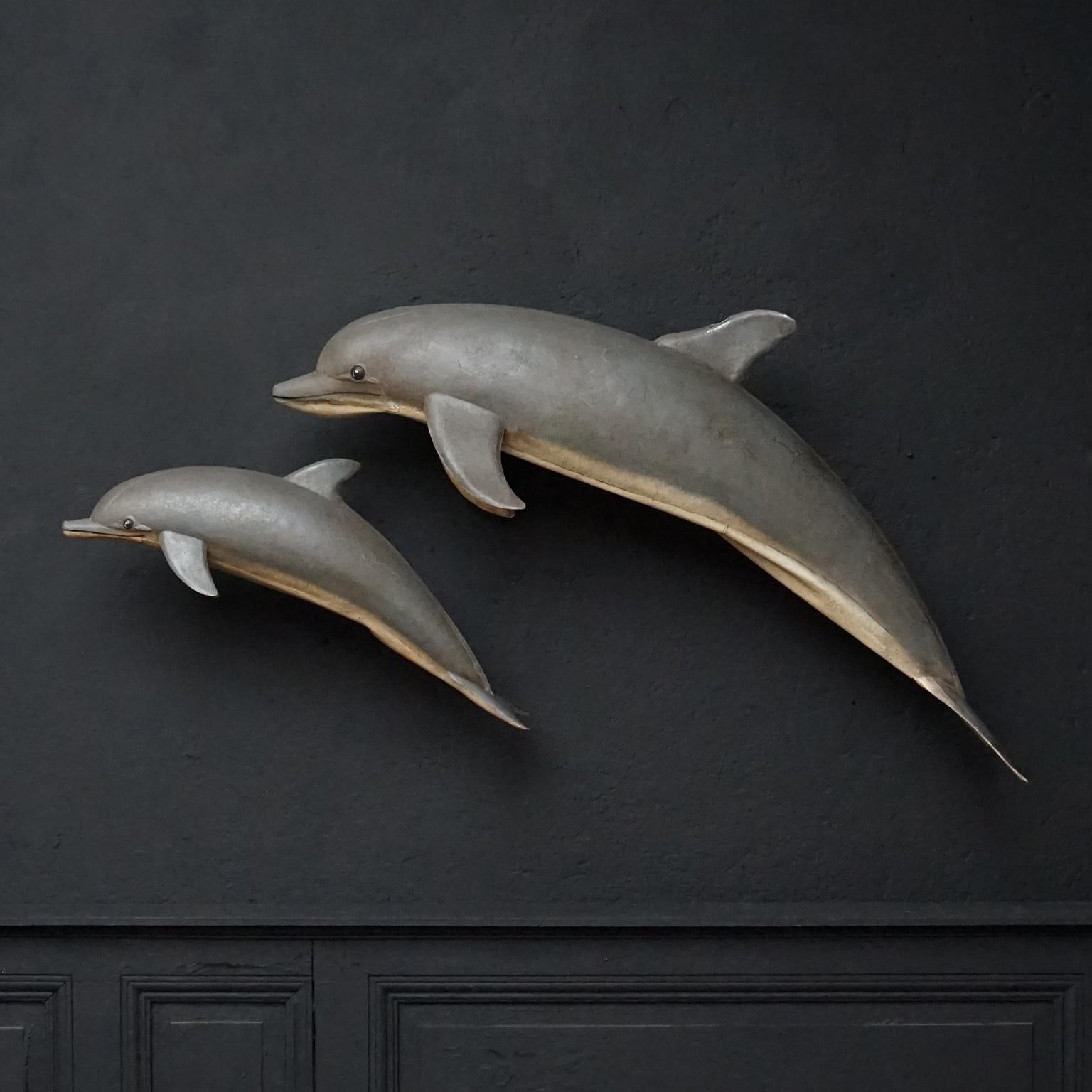 Fantastic set of two 1960s French grey painted tin advertising dolphins, perfect to decorate your wall at home, a store or a restaurant with. 
The mama and the baby dolphin are in good vintage condition and made of tin. 
They both have iron