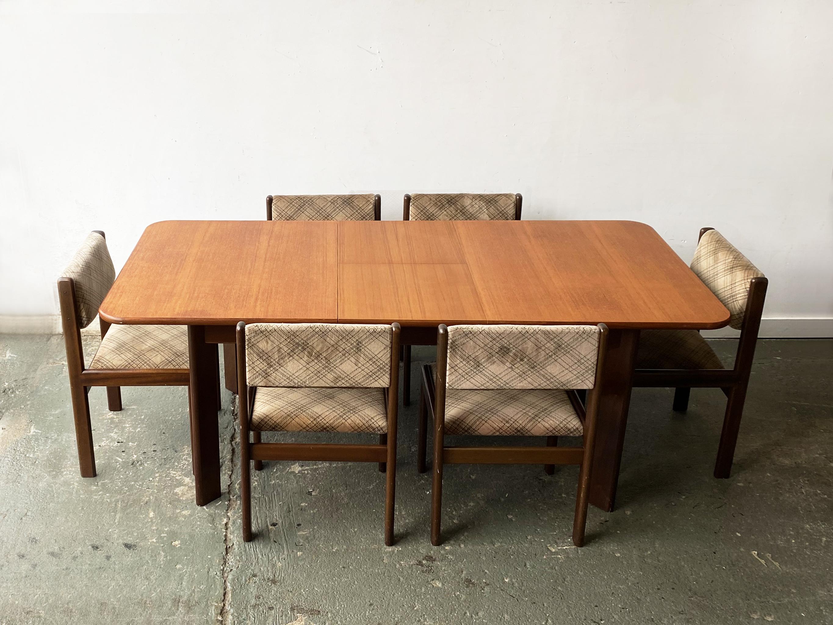 A G plan extending dining table, with the matching 6 dining chairs with the original upholstery.

The design s not typical G Plan. The table has wide angled legs and the chairs have a rounded corner dark wood frame.

G Plan collaborated with Danish