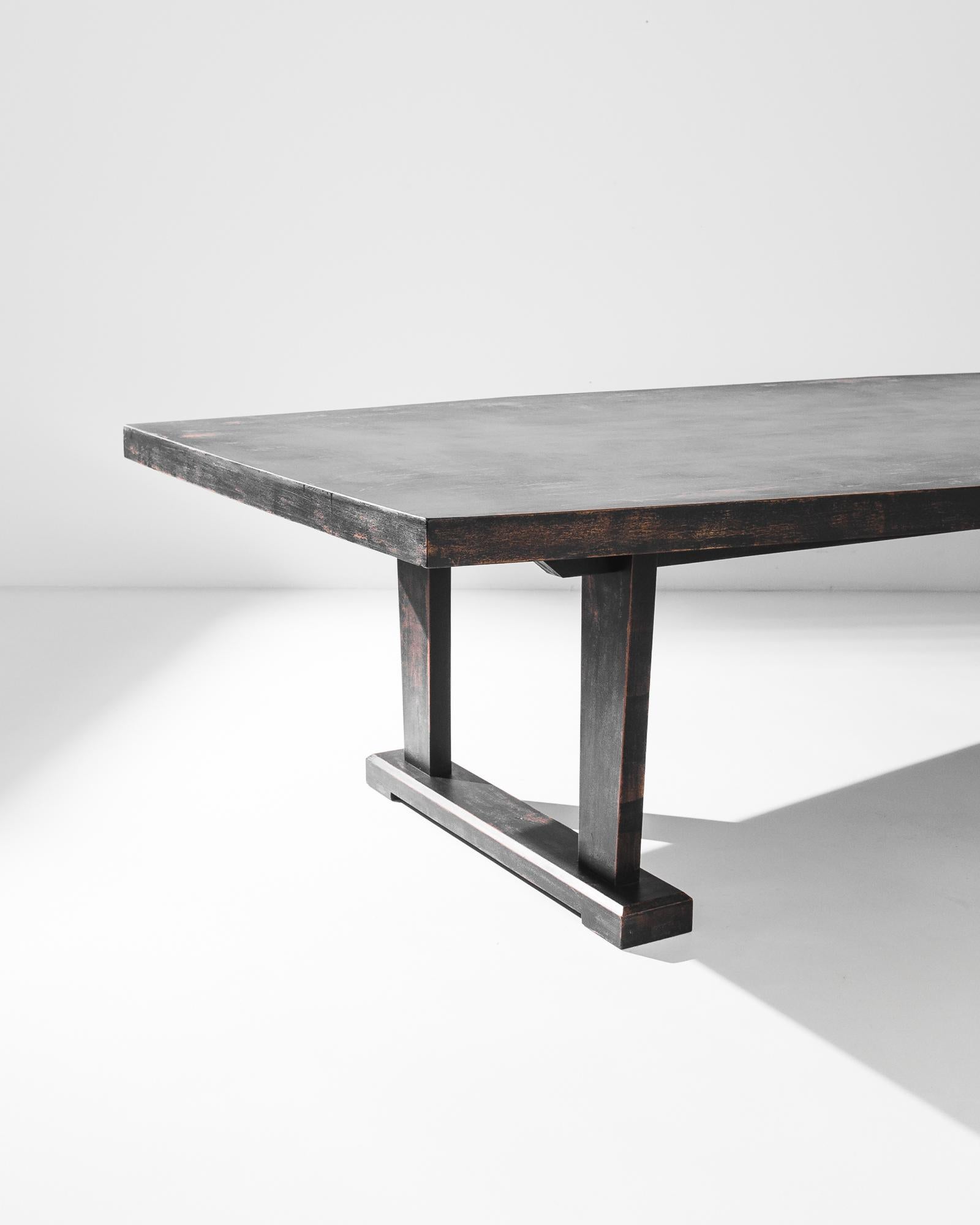 A wooden dining table from 1960s Germany with a stylish Mid-Century Modern aesthetic. A long tabletop sits atop a pair of trestle legs; straight lines and right-angled corners give a clean inflection to the sturdy silhouette. The black-painted