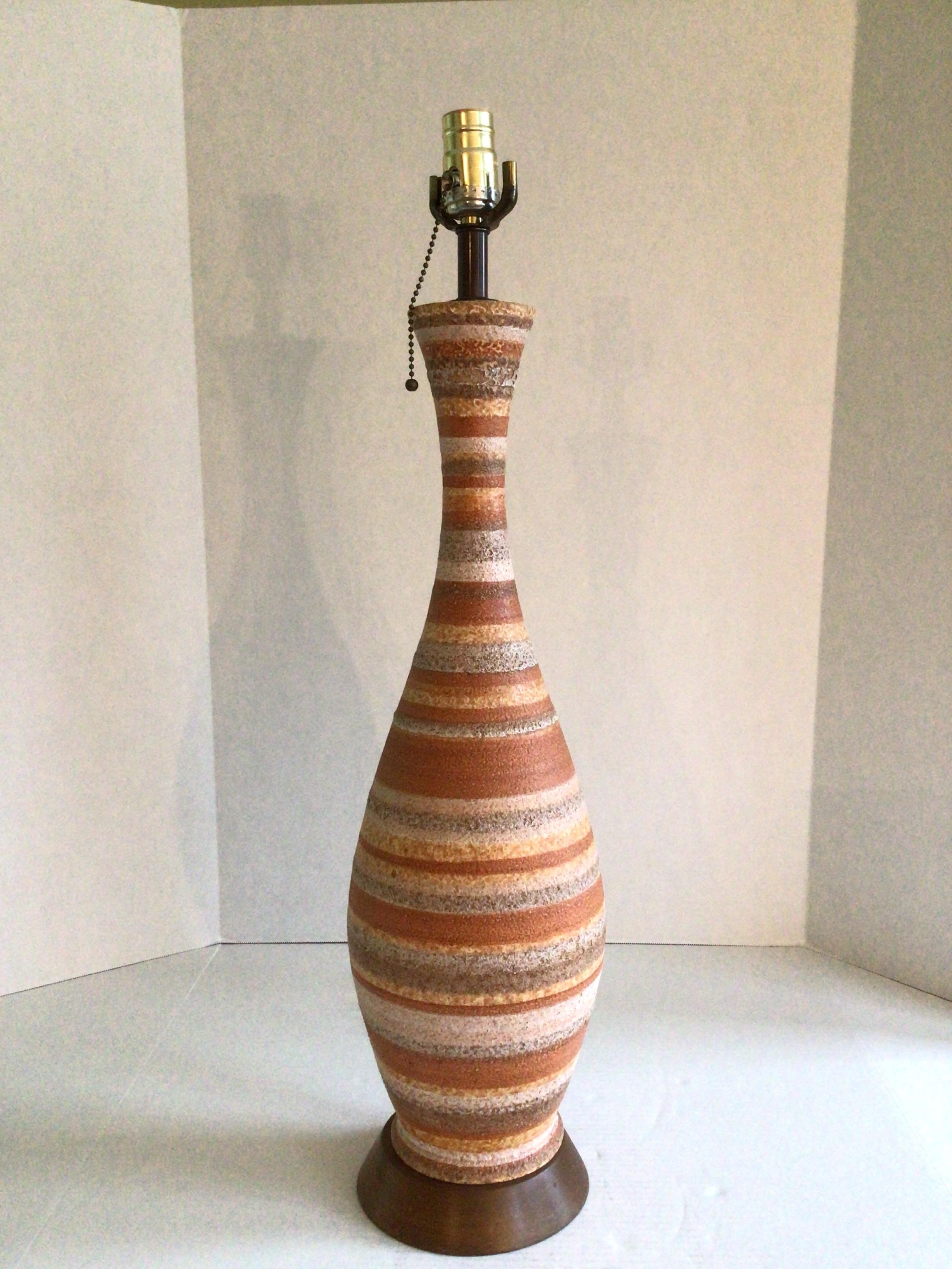 Lámpara de mesa de cerámica esmaltada de mediados de siglo de 1960 con base de madera 
Rayas salmón/melocotón, gris, marrón, crema/amarillo
El esmalte texturizado añade calidez e interés 
Esta lámpara funcionaría bien en un entorno contemporáneo y