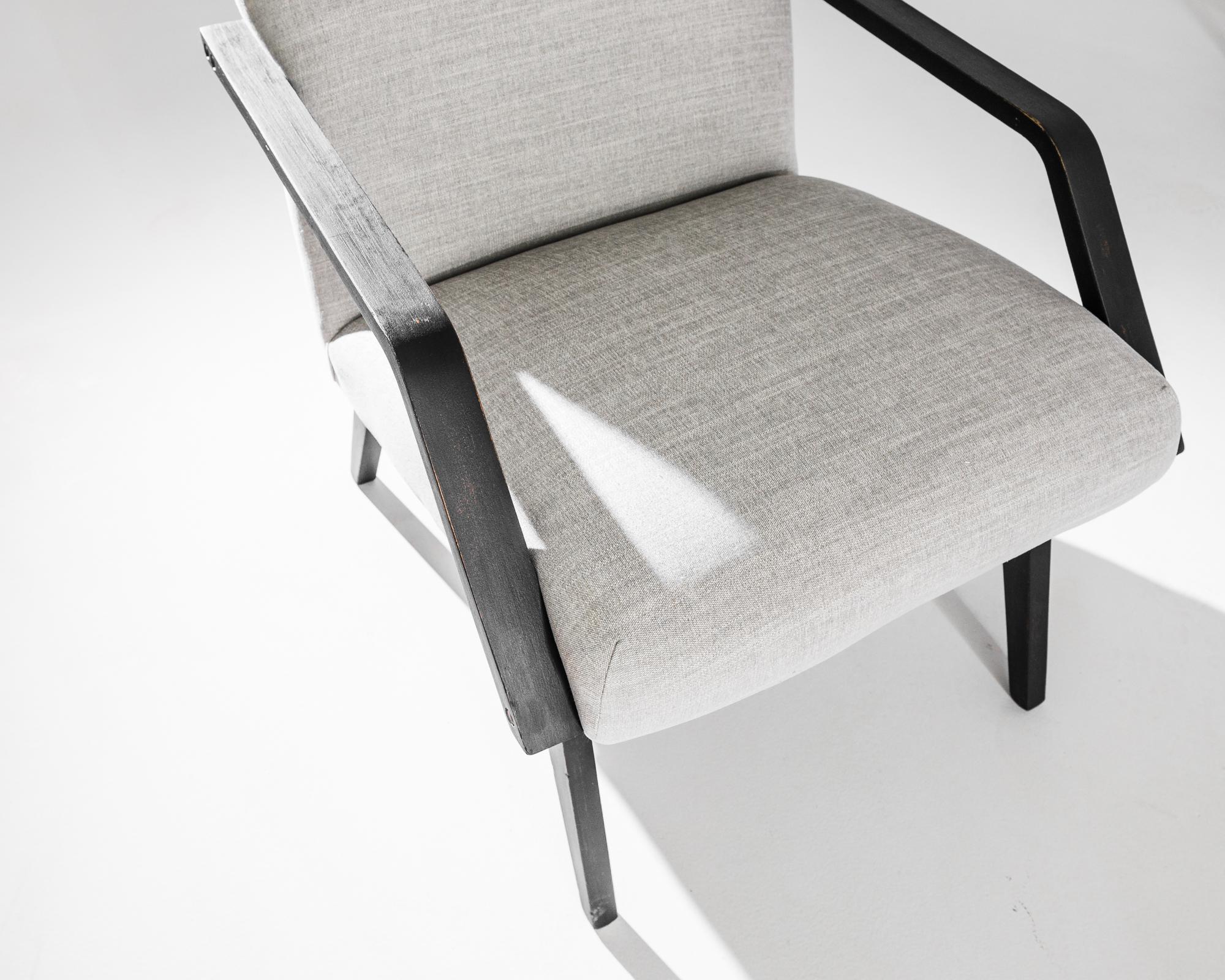A pair of armchairs produced in the former Czechoslovakia. This 1960s design is re-upholstered in an updated grey fabric, the neutral tone was chosen to compliment the elegant black of the hardwood frame. Comfortable angles and clean lines, the
