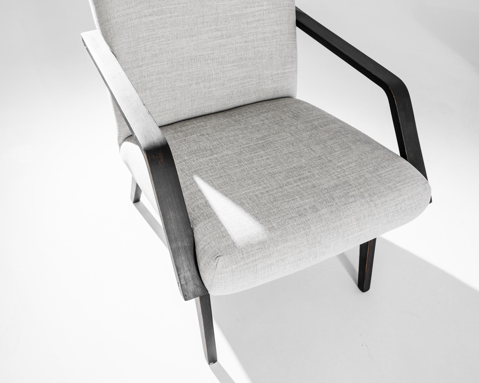 A pair of armchairs produced in the former Czechoslovakia. This 1960s design is re-upholstered in an updated grey fabric, the neutral tone was chosen to compliment the elegant black of the hardwood frame. Comfortable angles and clean lines, the