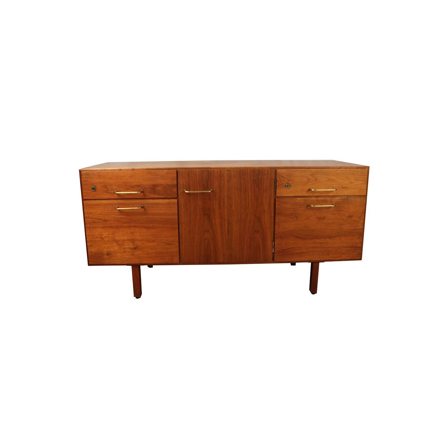 An exceptional and solid midcentury walnut file cabinet/credenza by iconic designer Jens Risom, circa 1960s, manufactured in the USA. This absolutely stunning piece features gorgeous walnut wood grain, stylish brass pulls and door hinges, a low