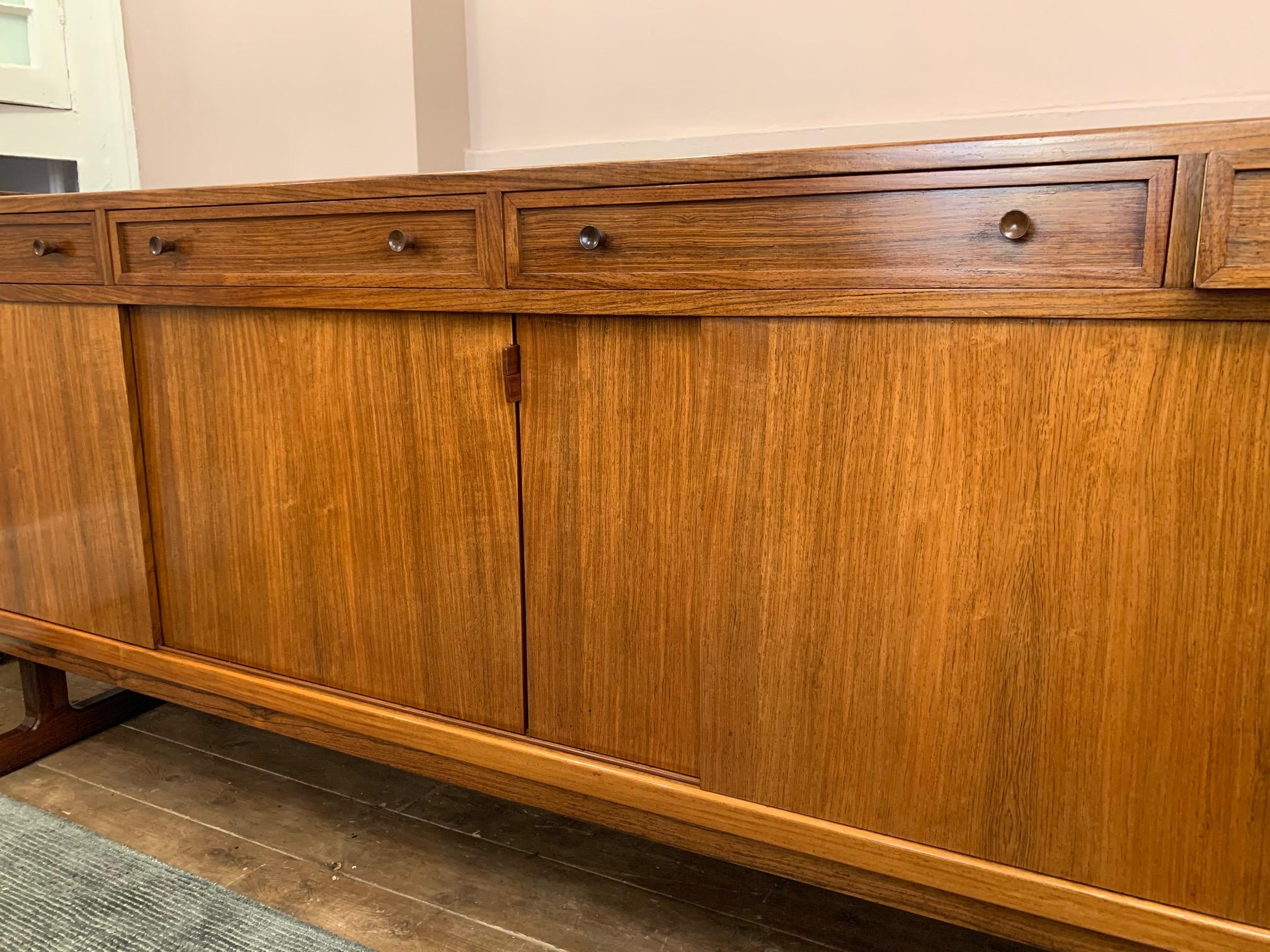 A beautiful large 1960s Danish rosewood sideboard with four individual drawers with two feature turned handles it open each one. The drawers sit over four sliding doors with turned handles on the end panels and an interesting detailed handle on each