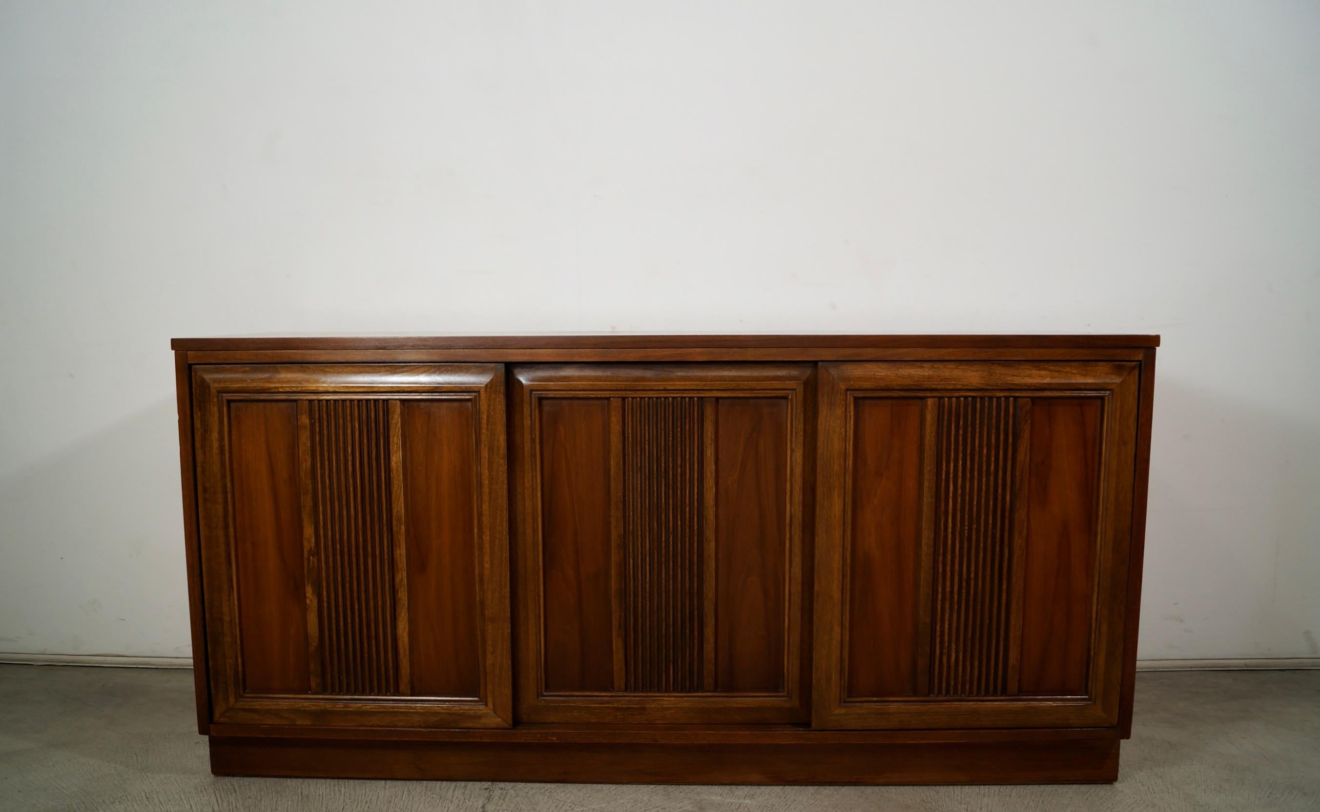 Vintage Midcentury Modern Brutalist credenza for sale. From the 1960's, and has the original finish still beautifully intact. It's made of walnut with a walnut finish, and is really well made. It has three sliding cabinet doors, and is the perfect