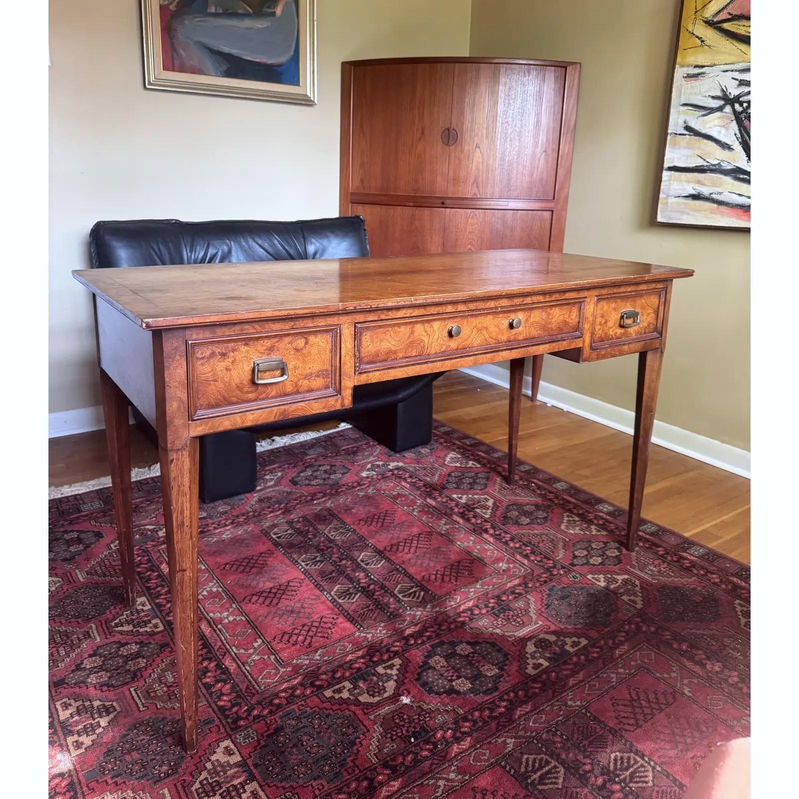 Elegant Mid-Century Modern writing desk by Henredon, c. 1960s, featuring a richly figured burl wood veneer. A finely crafted piece, it showcases three drawers with brass hardware, offering functional storage with a refined, minimalist silhouette.