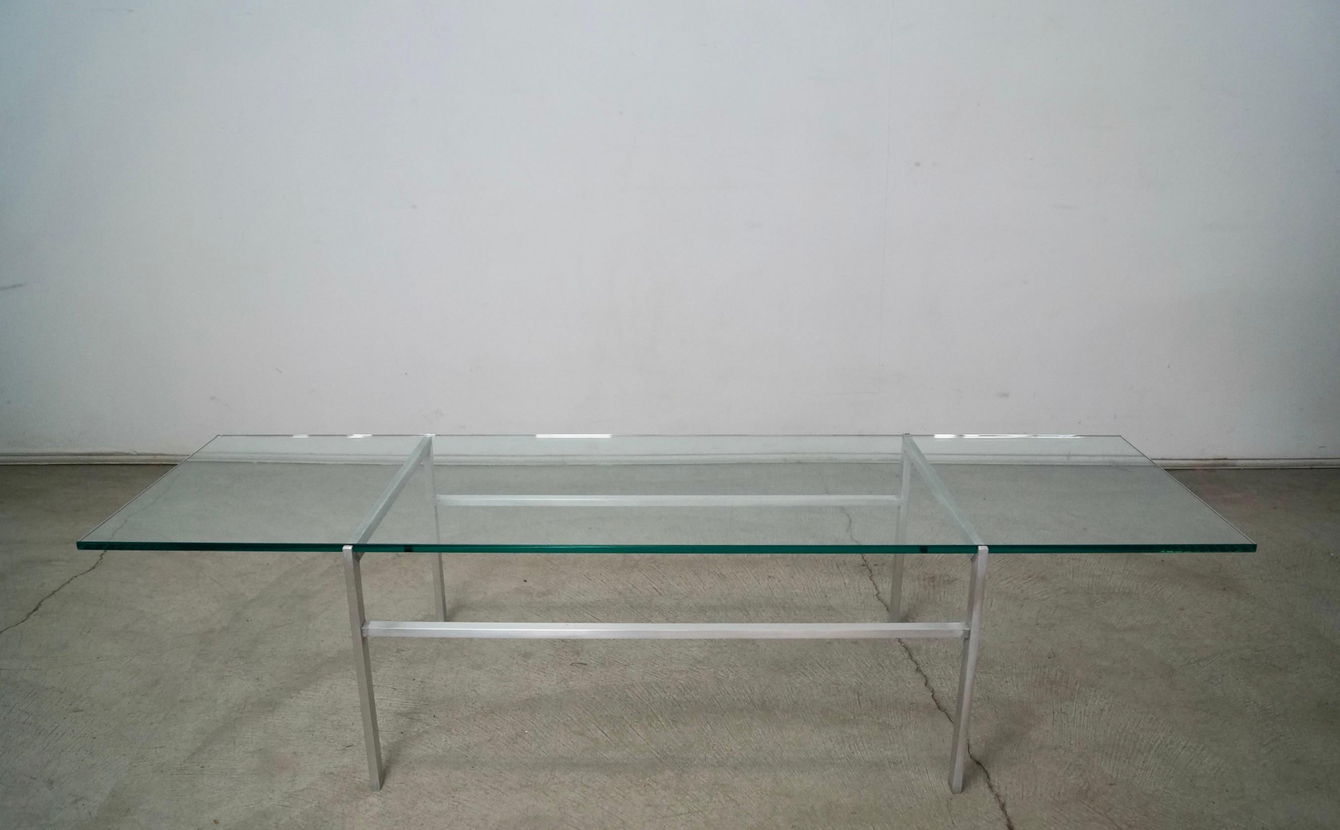 Vintage Midcentury Modern coffee table for sale. Manufactured in the 1960's, and has an aluminum base with a floating thick glass top. It has a very beautiful and sleek aesthetic, and is in the manner of Gerald McCabe and Herman Miller designs. The