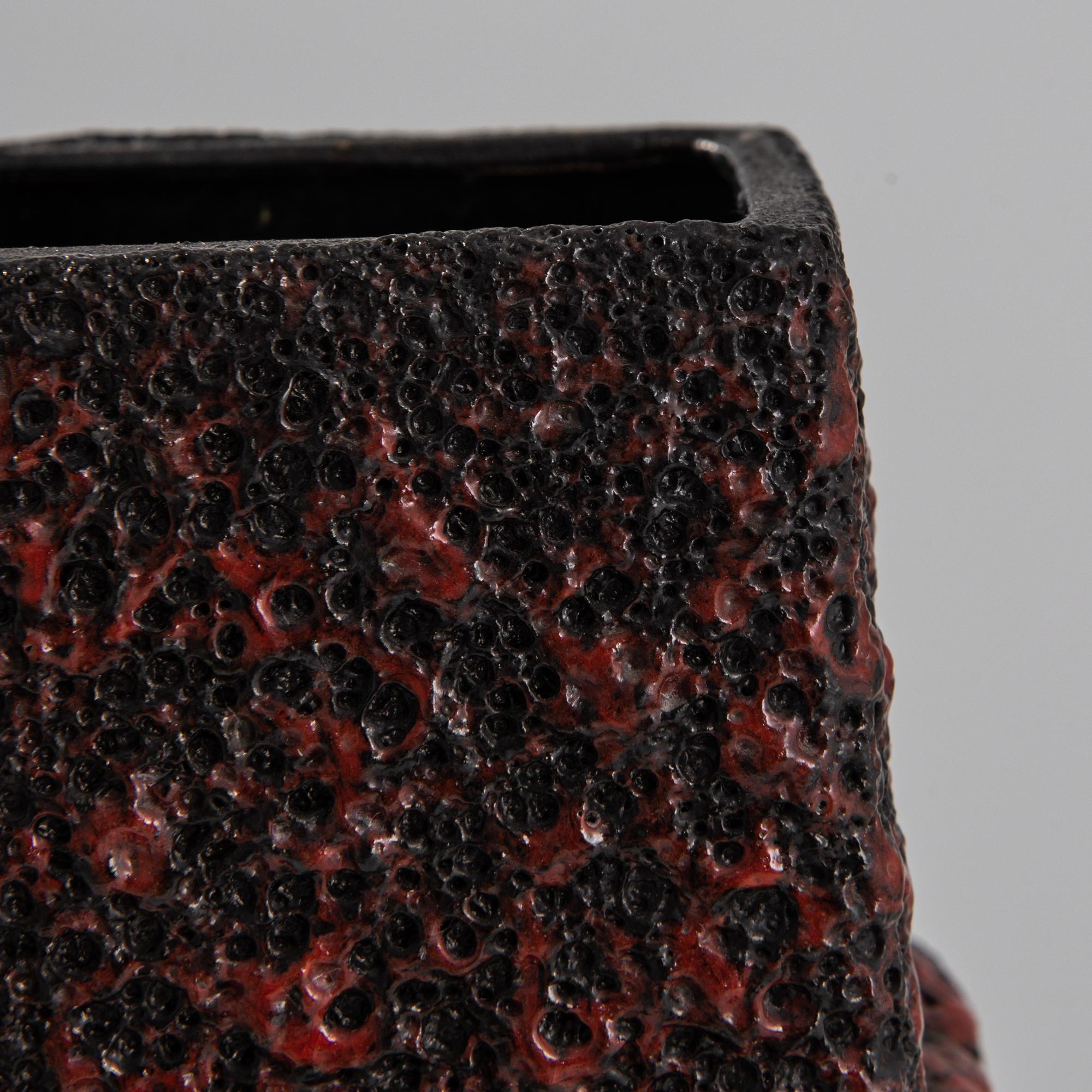 Encrusted with a tactile red glaze, carmine infused with sooty black recalls the heat of roiling lava. Frozen in motion, the liquid laze and organic form capture the fluidity of ceramic material. An exceptional example of 1960s German mid-century