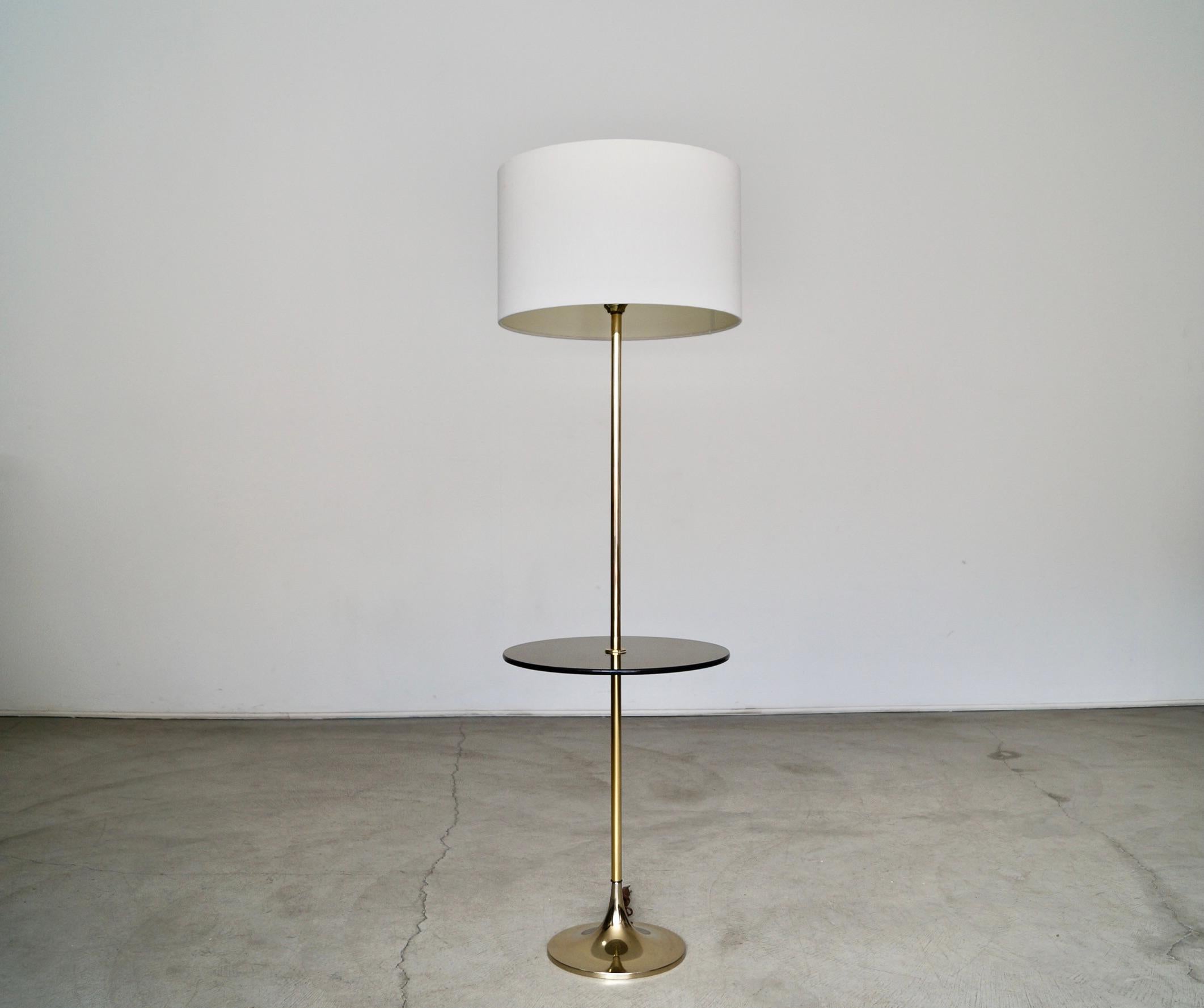Vintage 1960’s Mid-century Modern floor lamp for sale. Manufactured by Laurel Lighting in the 1960’s, and in excellent condition. It’s the classic tulip lamp with a brass base and stem, and has a smoked glass end table. The glass is in amazing