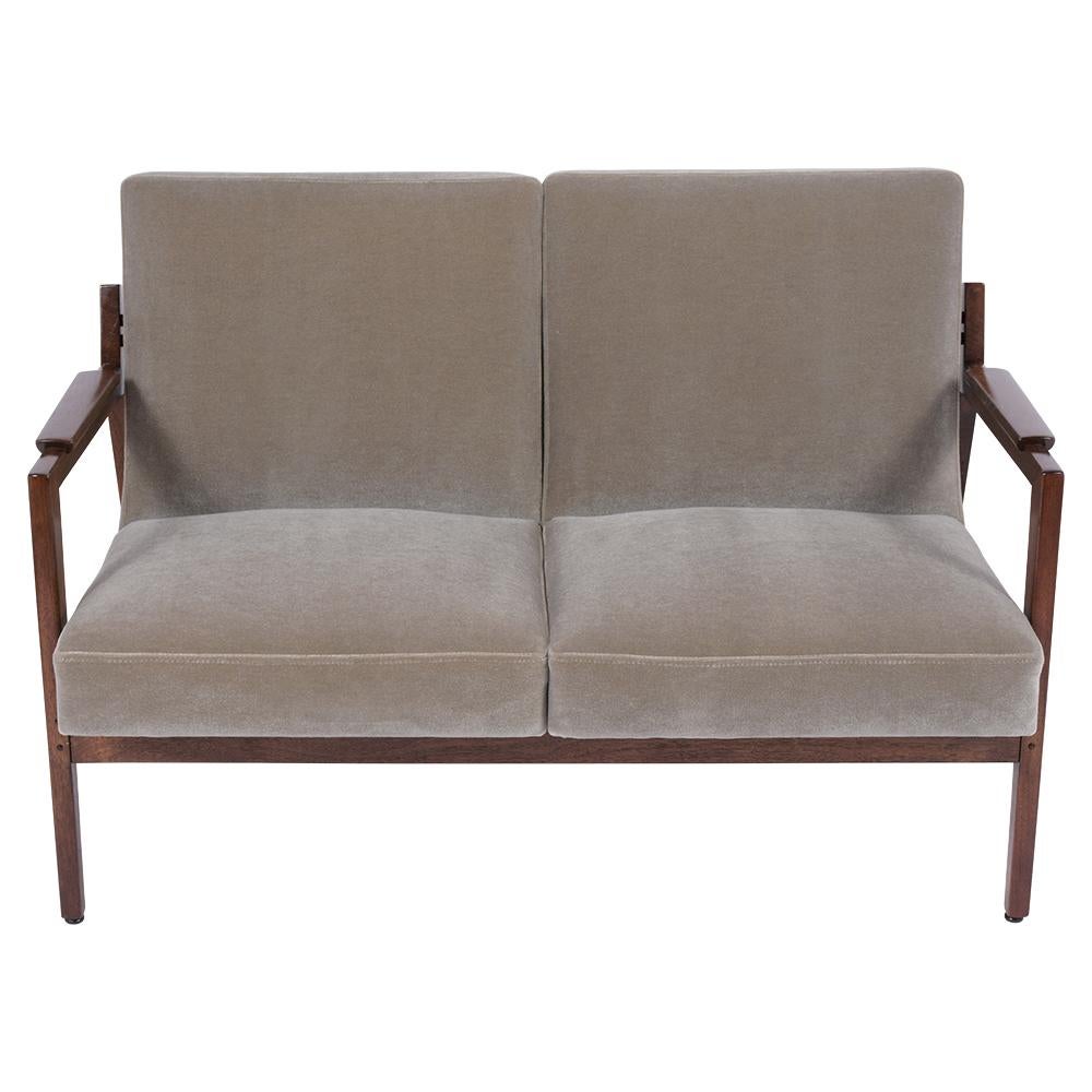 This fabulous 1960's Mid Century Danish style Loveseat is crafted out of walnut wood newly stained in mahogany color with a lacquered finish. This sofa features a sleek carved frame. Supportive slanted backrest and is newly upholstered in an olive