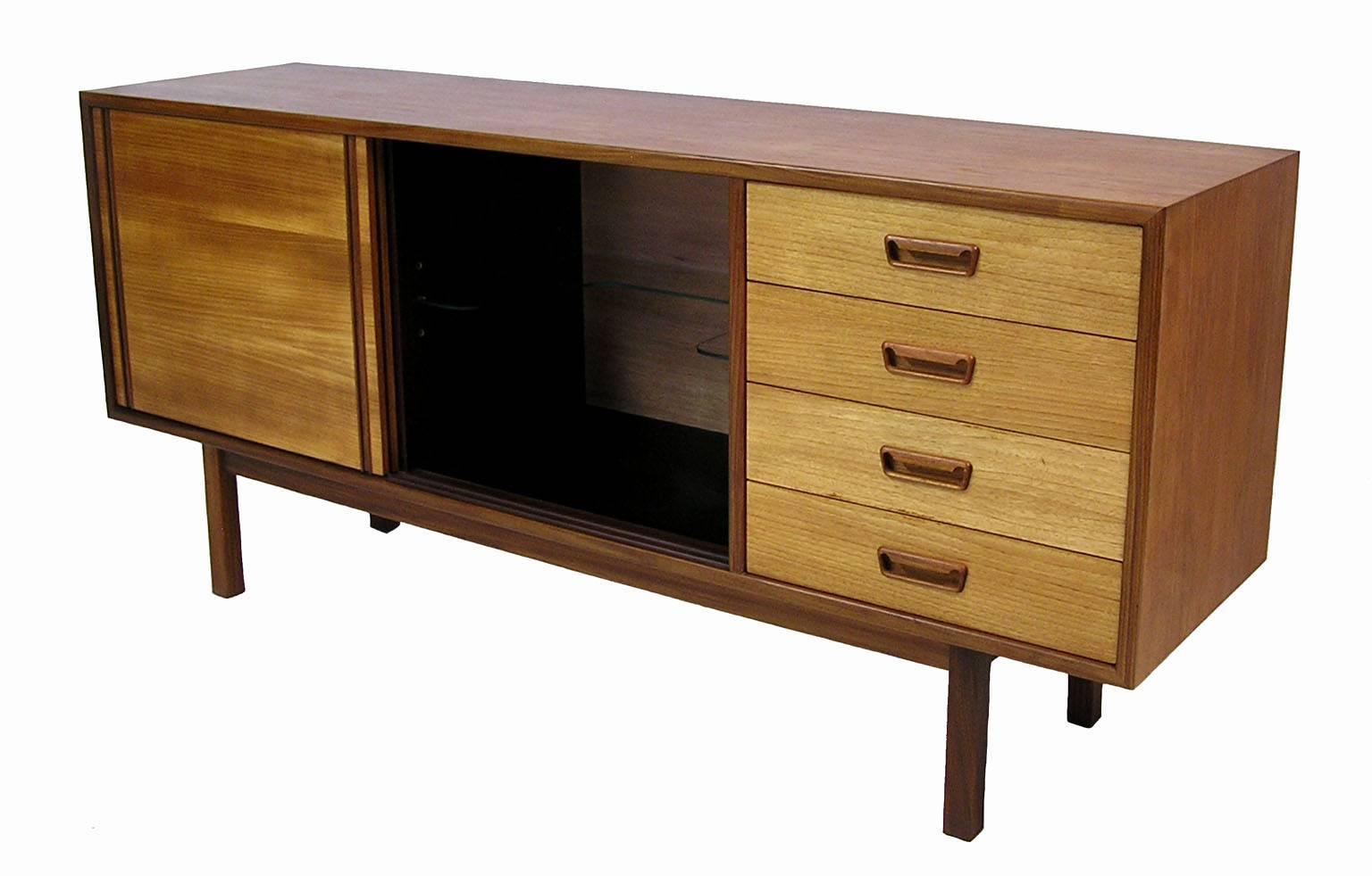 A gorgeous low teak sideboard from the 1960s Danish modern inspired era by RS Associates of Canada. Stylish clean lines with a contrasting tone and beautifully sculpted pulls. Features a center bar style compartment with a black laminate bottom and