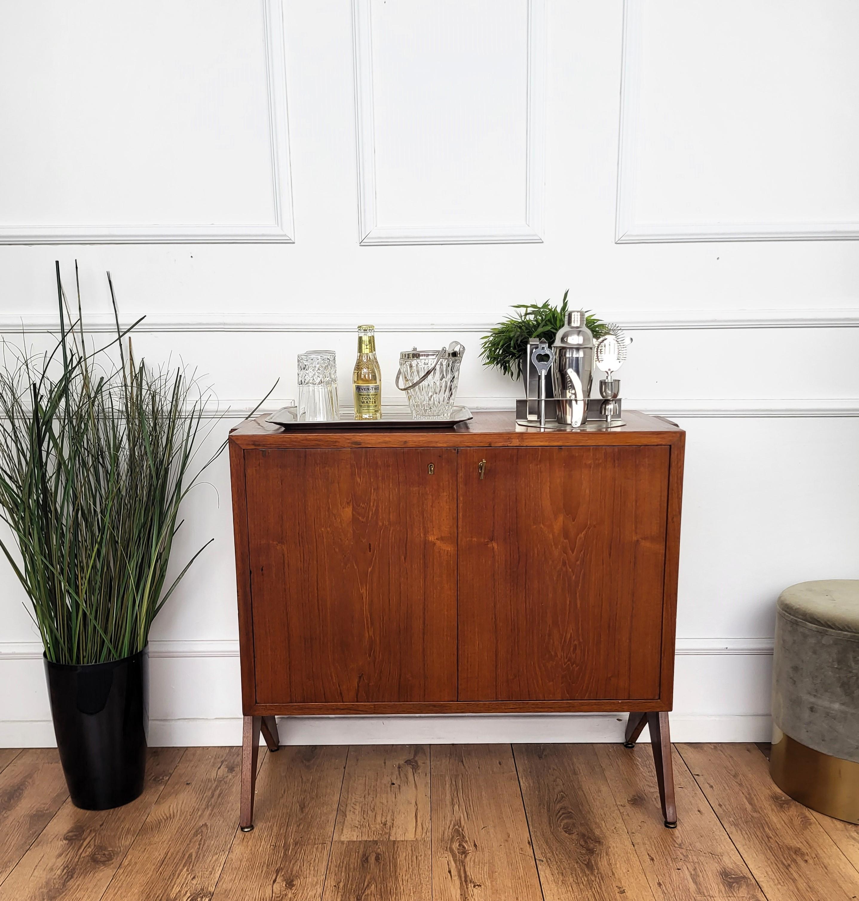 Elegantissimo mobile da cocktail da bar moderno del Mid-Century, in legno pregiato, con ripiani superiori, sportelli centrali con portaoggetti interno, due cassetti inferiori, il tutto evidenziato dalle tipiche gambe laterali intagliate del