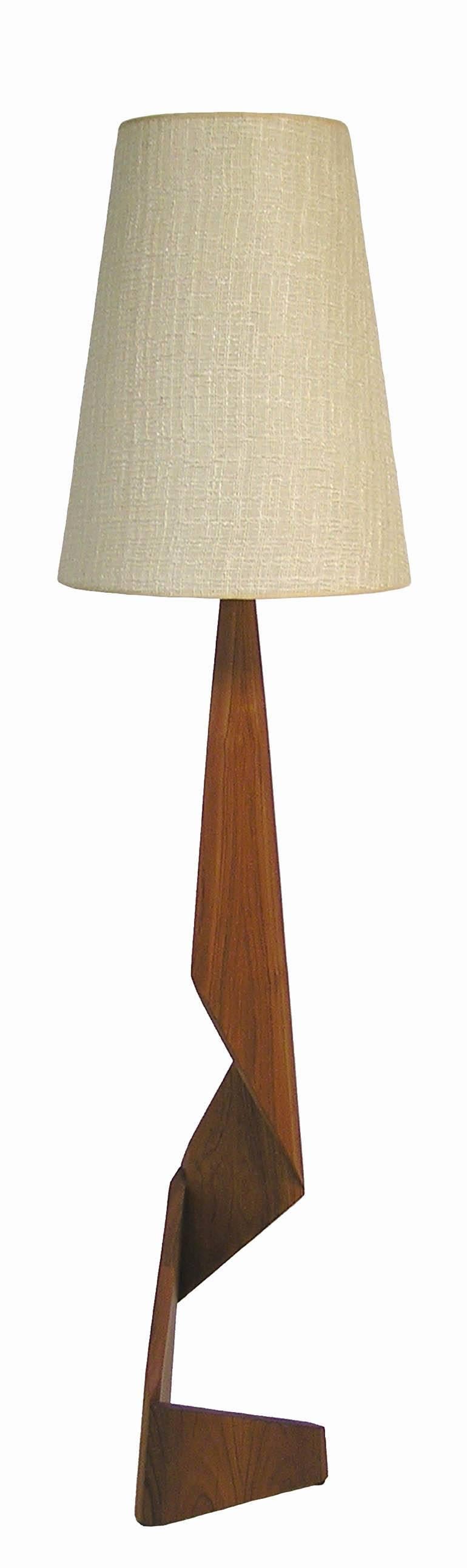 A pair of uniquely designed zig zag teak floor lamps from the 1960s Danish Mid-Century Modern era. Amazing craftsmanship throughout featuring a sculpted geometrical solid teak base with original conical shade and three-way light socket. Base of both