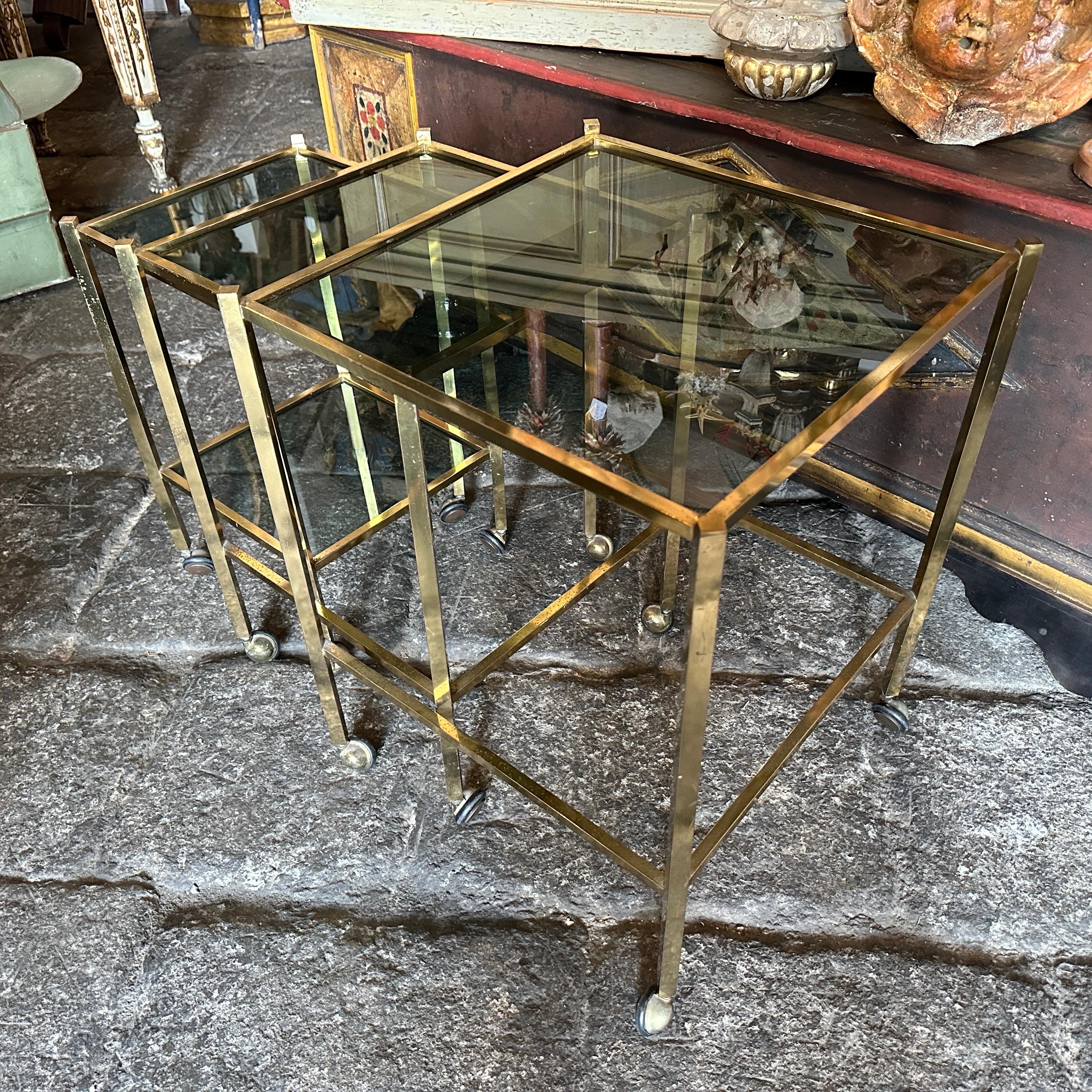 Set of three essential nesting tables designed and manufactured in Italy in the 1960s, brass in original patina and smoked glasses are in good conditions with small signs of use and age. The Nesting Tables are a highly desirable and visually