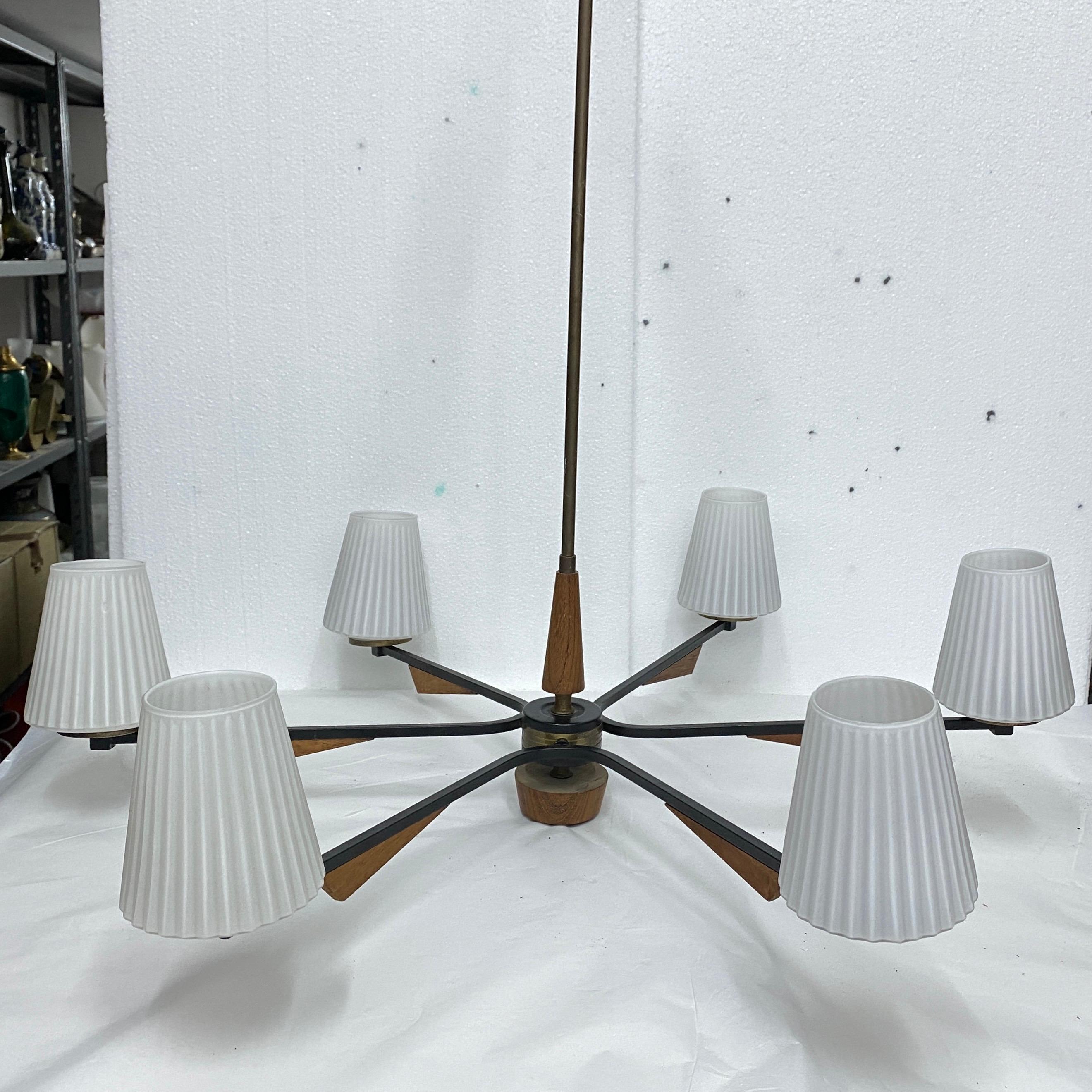 It's a teak, brass and glass six lights chandelier designed and manufactured in Italy in the Sixties, it has been checked and rewired by an electrician, it works both 110 240 volts and needs six regular e14 bulbs. This chandelier is highly sought