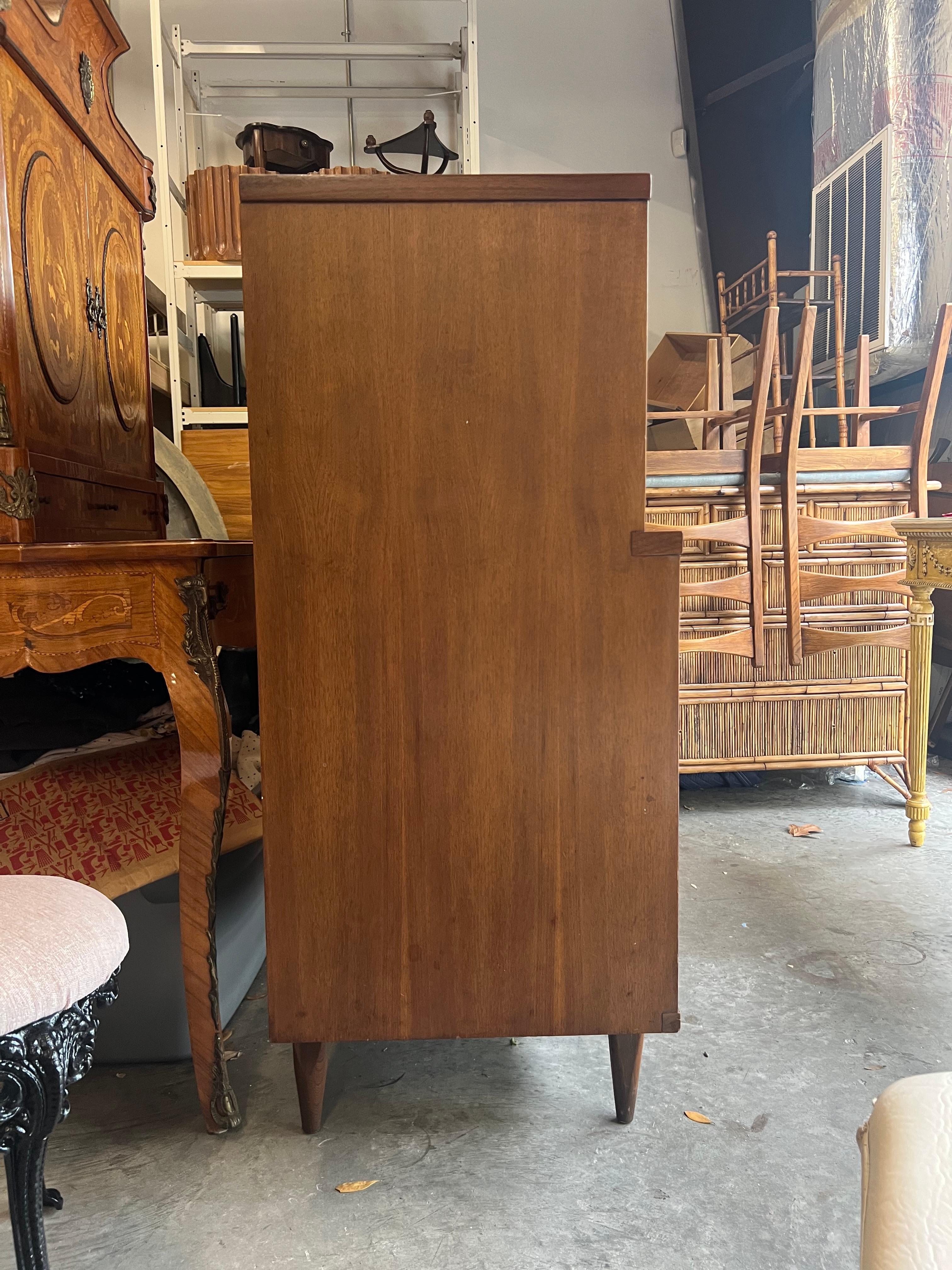 This beautiful mid-century highboy features the stunning design manufacturer Kent Coffey was so well known for. This piece for the Tableau furniture line features inlaid metal drawer pulls, sturdy hardwood construction, and stylish tapered legs.