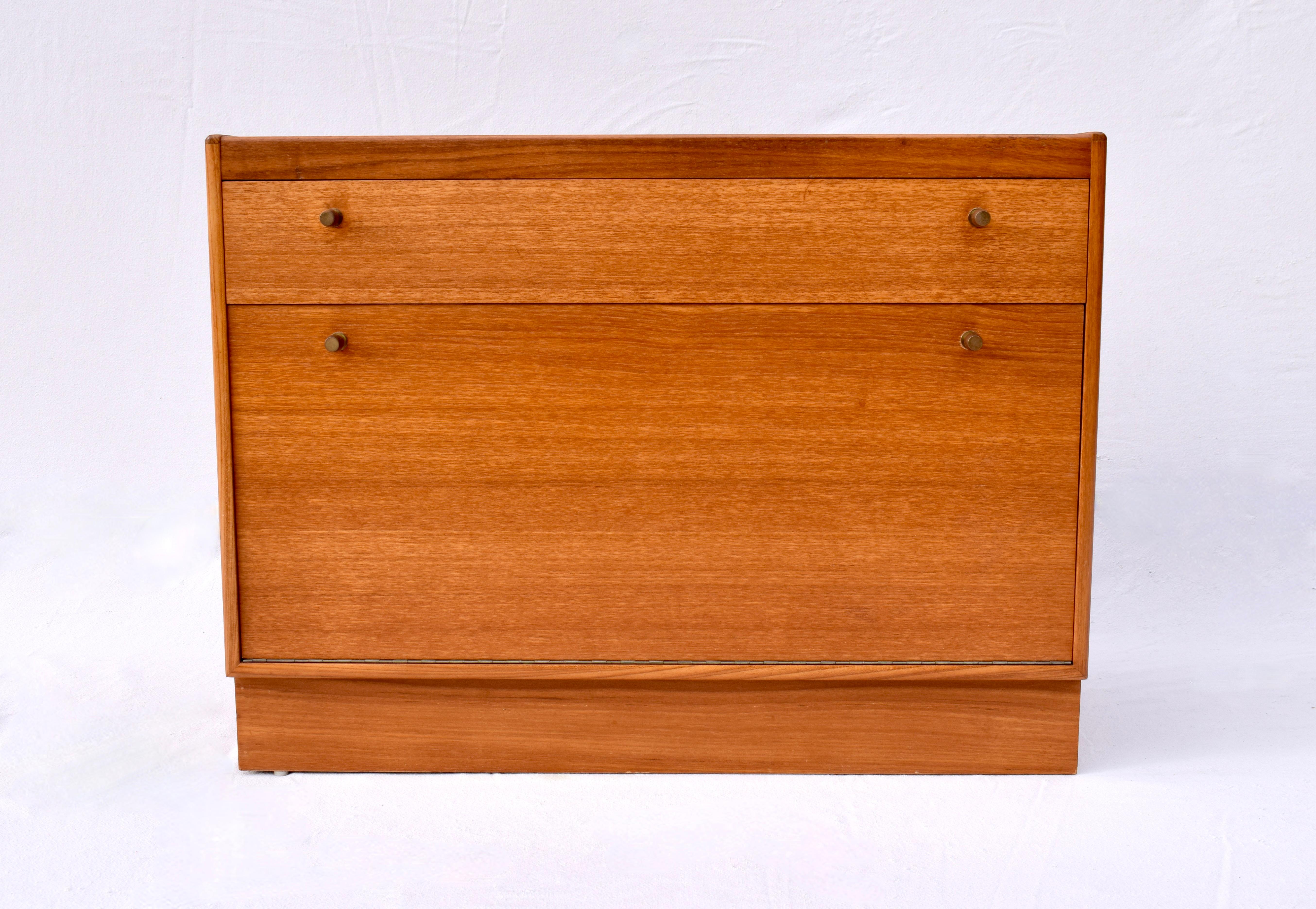 Mid 20th century Teak bar Cabinet or server featuring top utensil drawer, drop down lower cabinet on a plinth base. Multifunctional size suitable for use in various settings. Limited production by Turnidge of England circa 1960's;  signed.