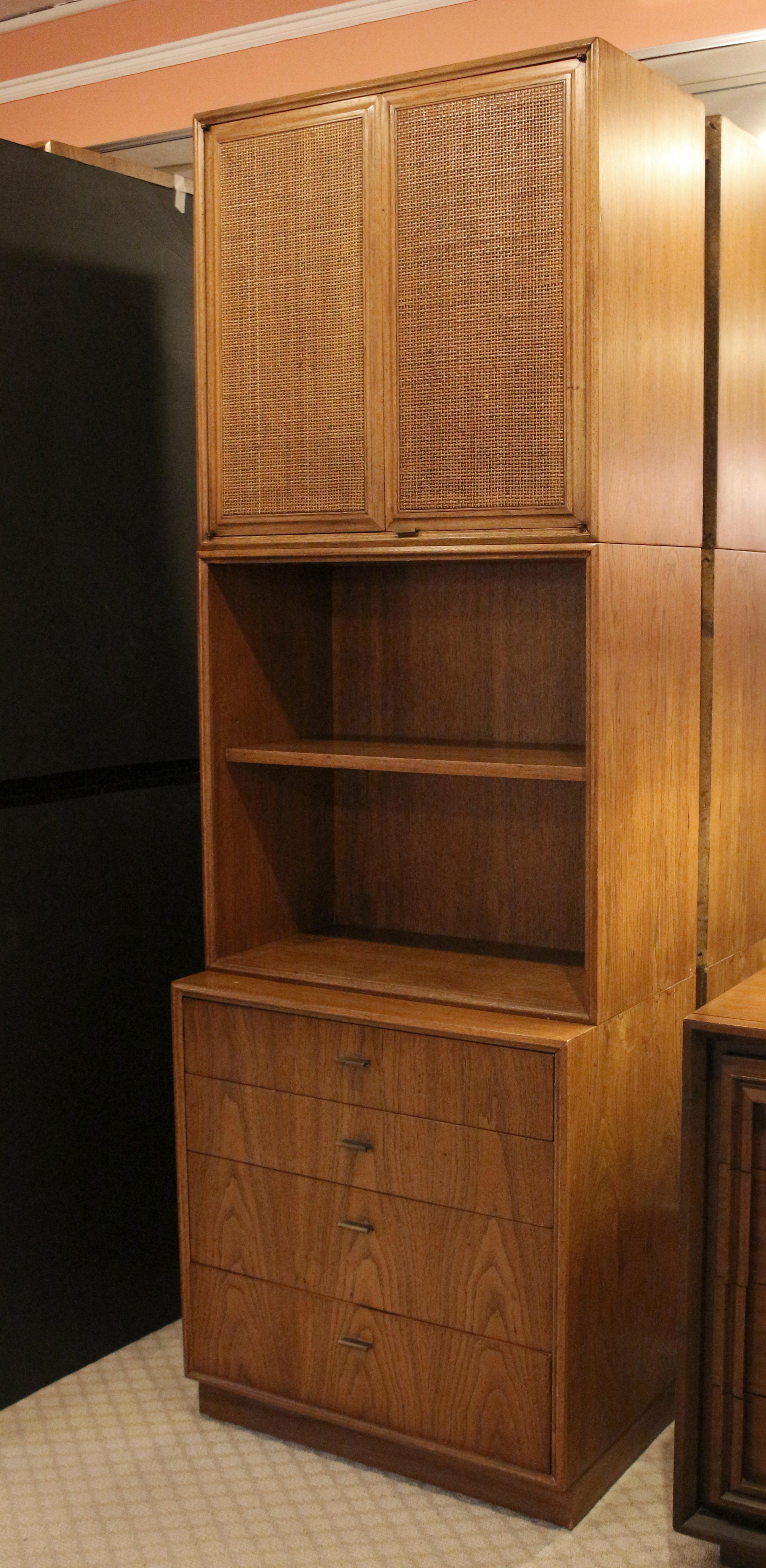 A significant quality c. 1960's mid-century modern three part cabinet on bookcase on chest paired on a plinth base. Made by Founders of solid pecan with cane panels and fine brass pulls, it was designed by Jack Cartwright. While not branded, it is