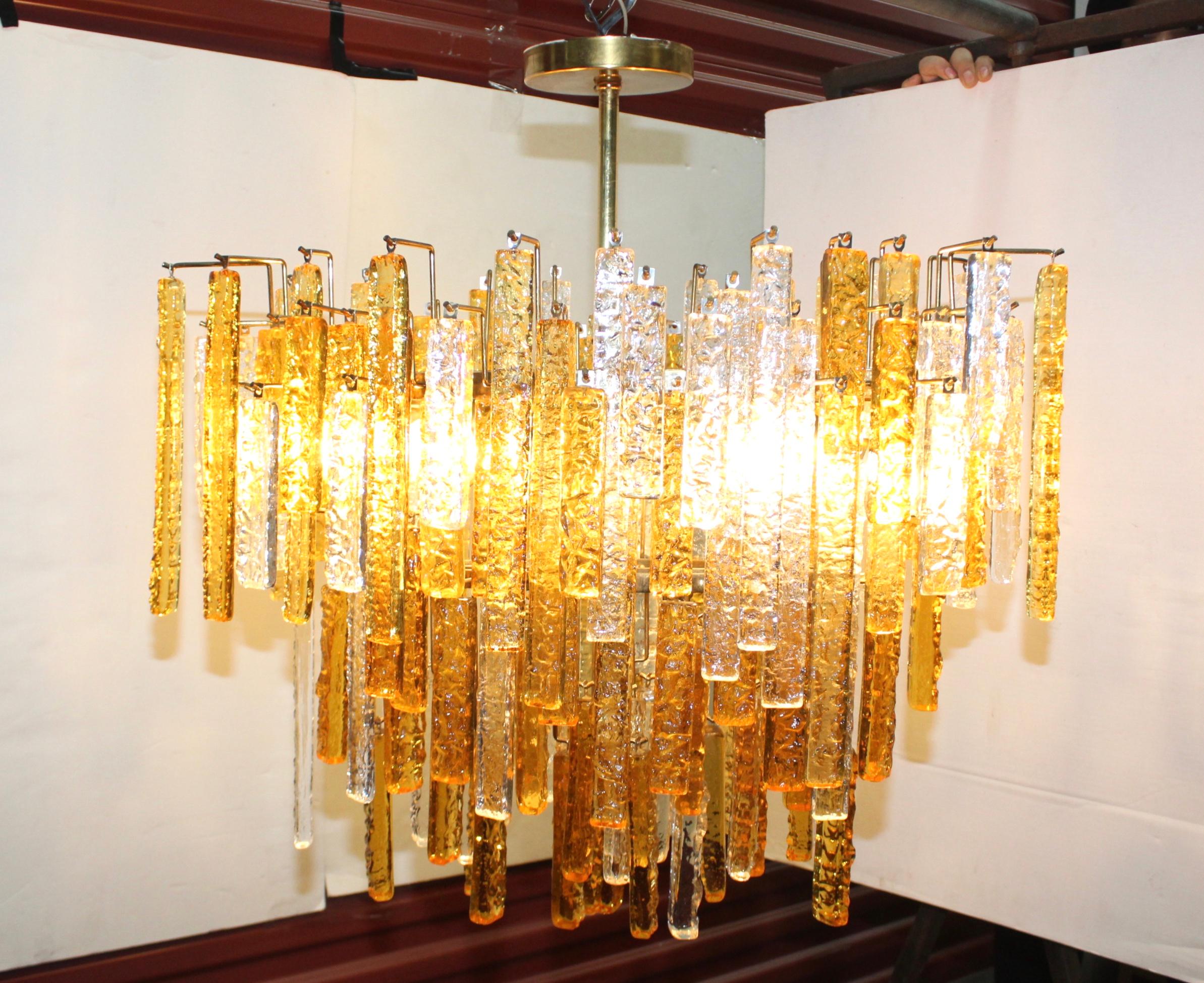 Superbe lustre en verre Venini des années 1960, de style moderne du milieu du siècle, avec un cadre en laiton et des tiges en verre ambré et transparent.