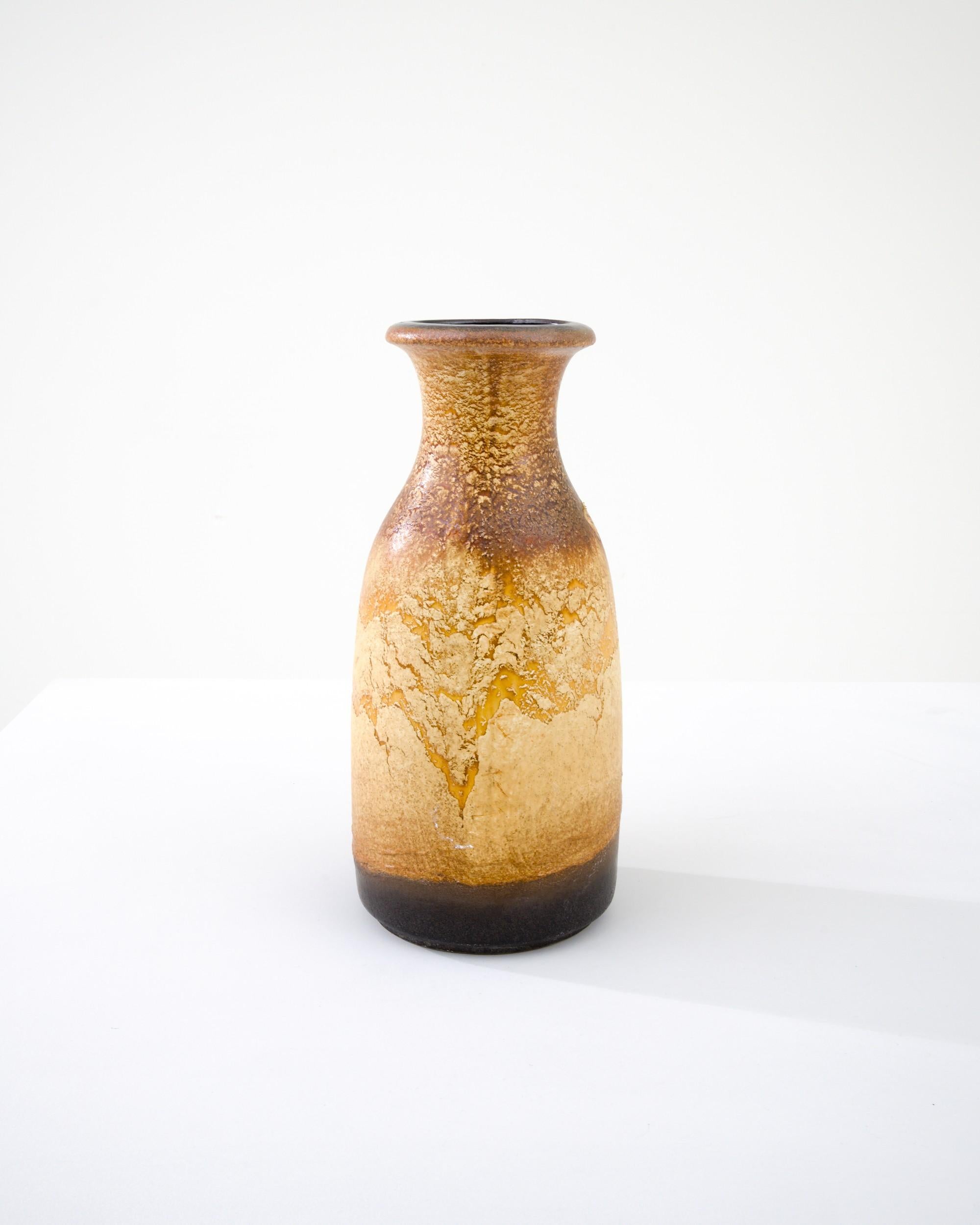 A ceramic vase from mid-20th century Germany. Neither large nor small, this studio made pot reflects the hand-held, and the handmade; the tactility of process and the artist's vision– realized on the potter’s wheel. Textured earth tones wrap the