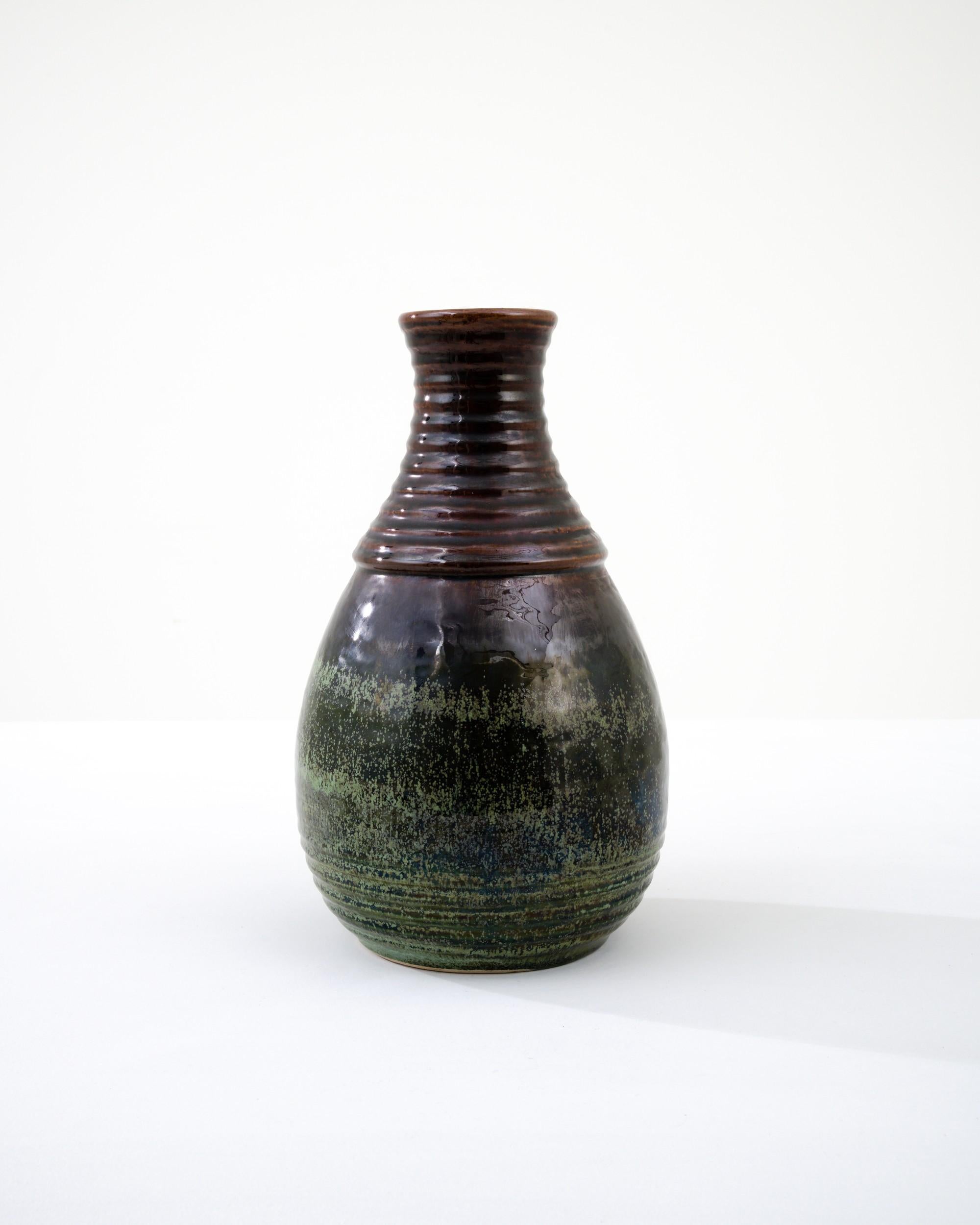 A ceramic vase from mid-20th century Germany. Neither large nor small, this studio made pot reflects the hand-held, and the handmade; the tactility of process and the artist's vision– realized on the potter’s wheel. Rich earth tones saturate the