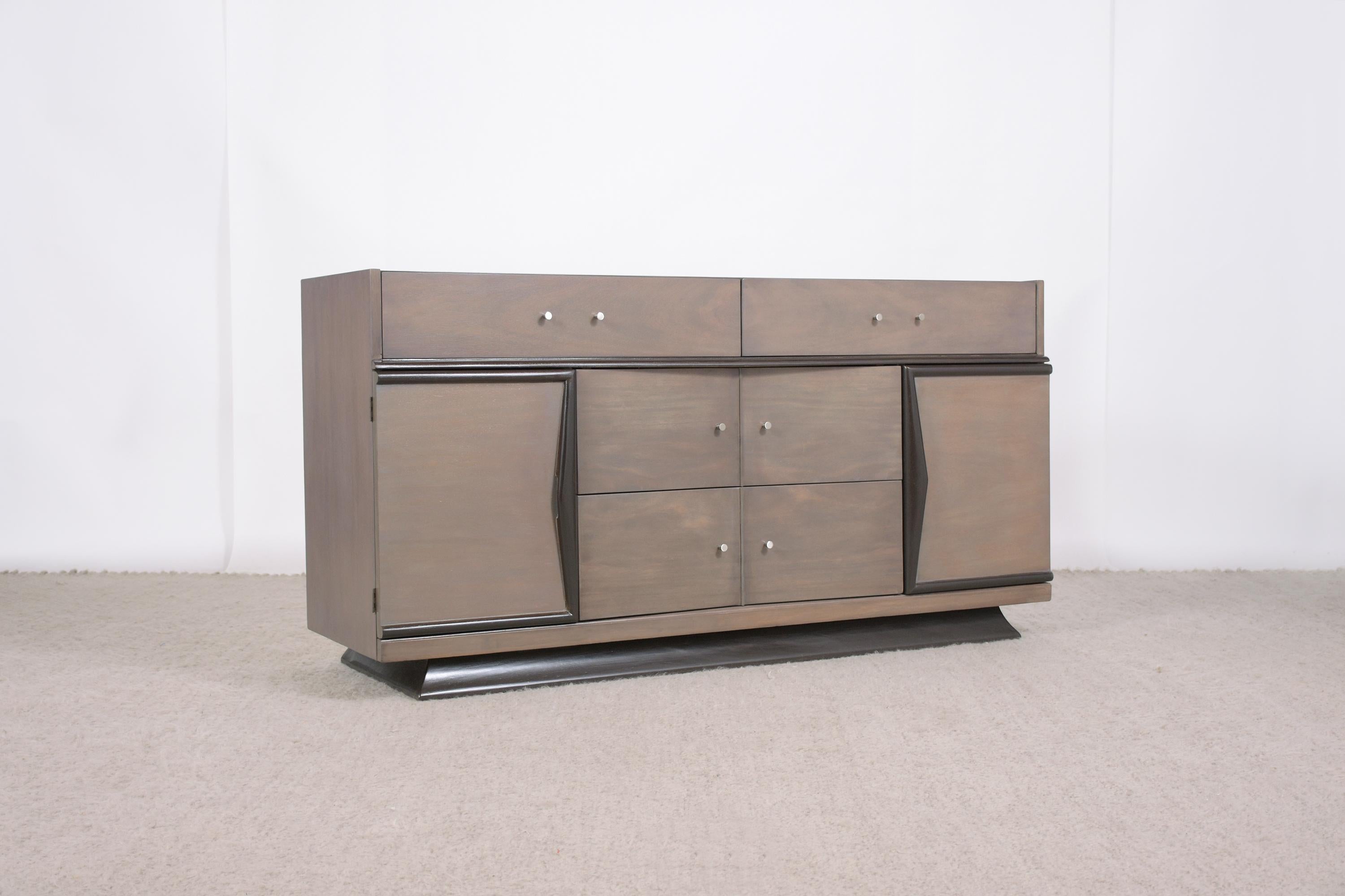 Experience the classic charm of the 1960s with our Vintage Mid-Century Modern Walnut Credenza, beautifully restored to its former glory. This exquisite piece, expertly crafted by seasoned artisans, showcases a luxurious mix of rich walnut wood and a