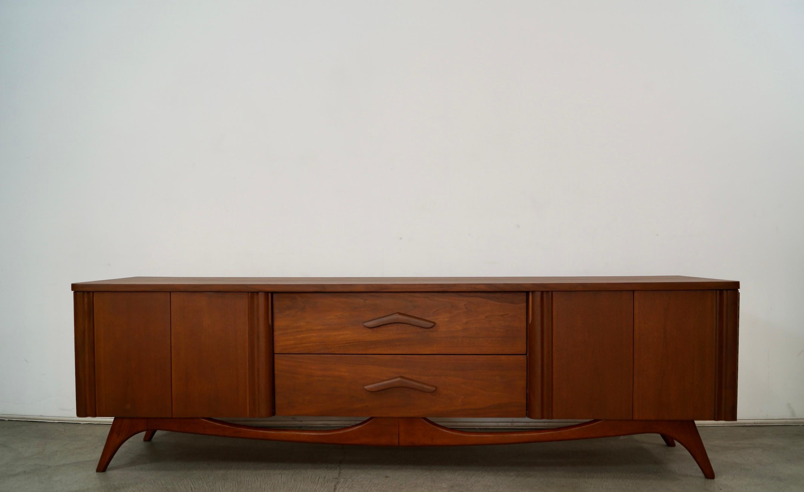 Vintage original Midcentury Modern long credenza for sale. Manufactured in the 1960's by Young Manufacturing Company, and has been refinished. It's made of walnut, and has an incredible design and aesthetic. It has a nice strong solid base with