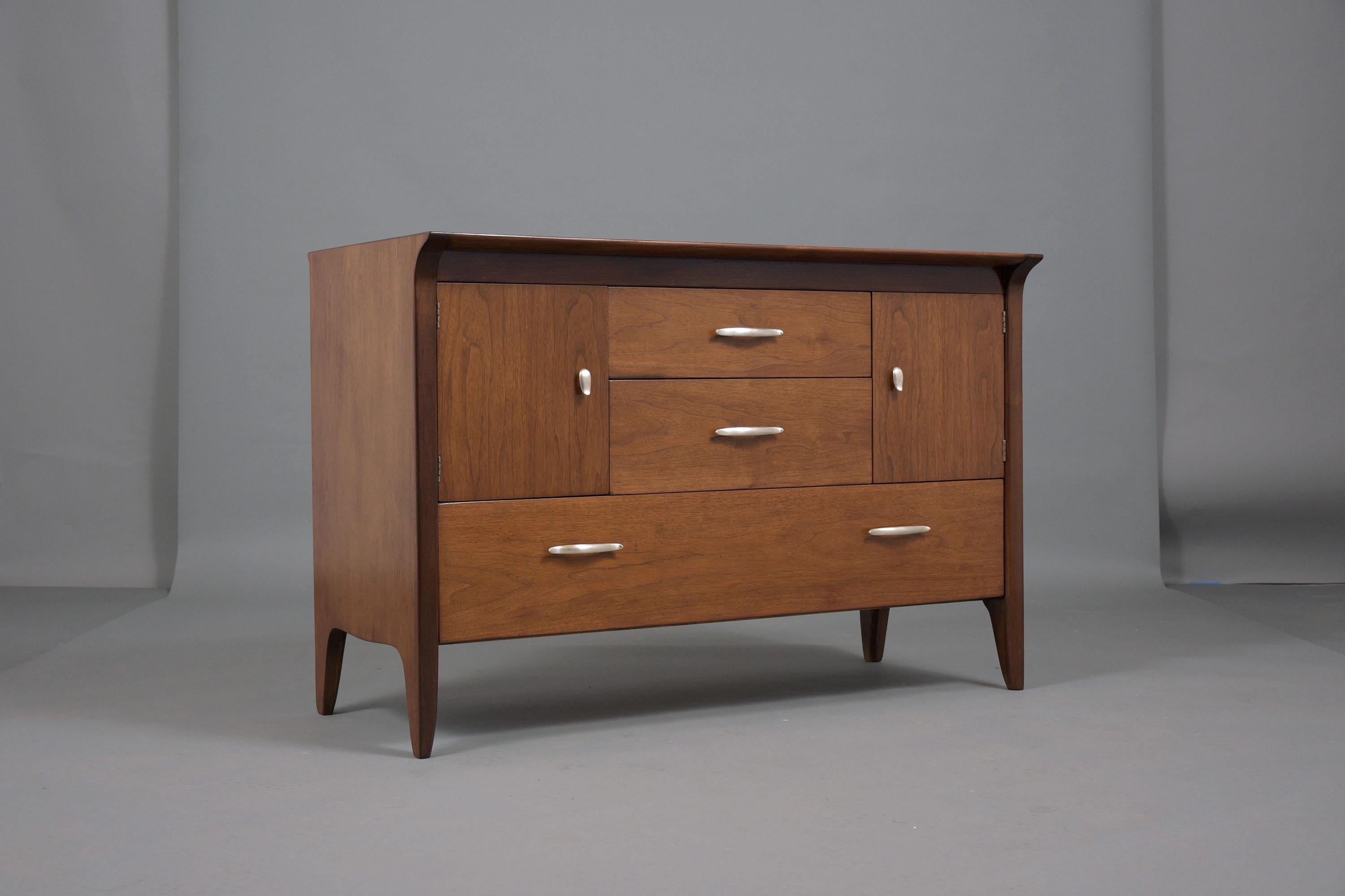Discover the timeless elegance of the 1960s with our Mid-Century Modern Walnut Chest of Drawers, a masterpiece that has been masterfully restored to reflect the unique blend of style and craftsmanship of the era. Crafted from premium walnut, this