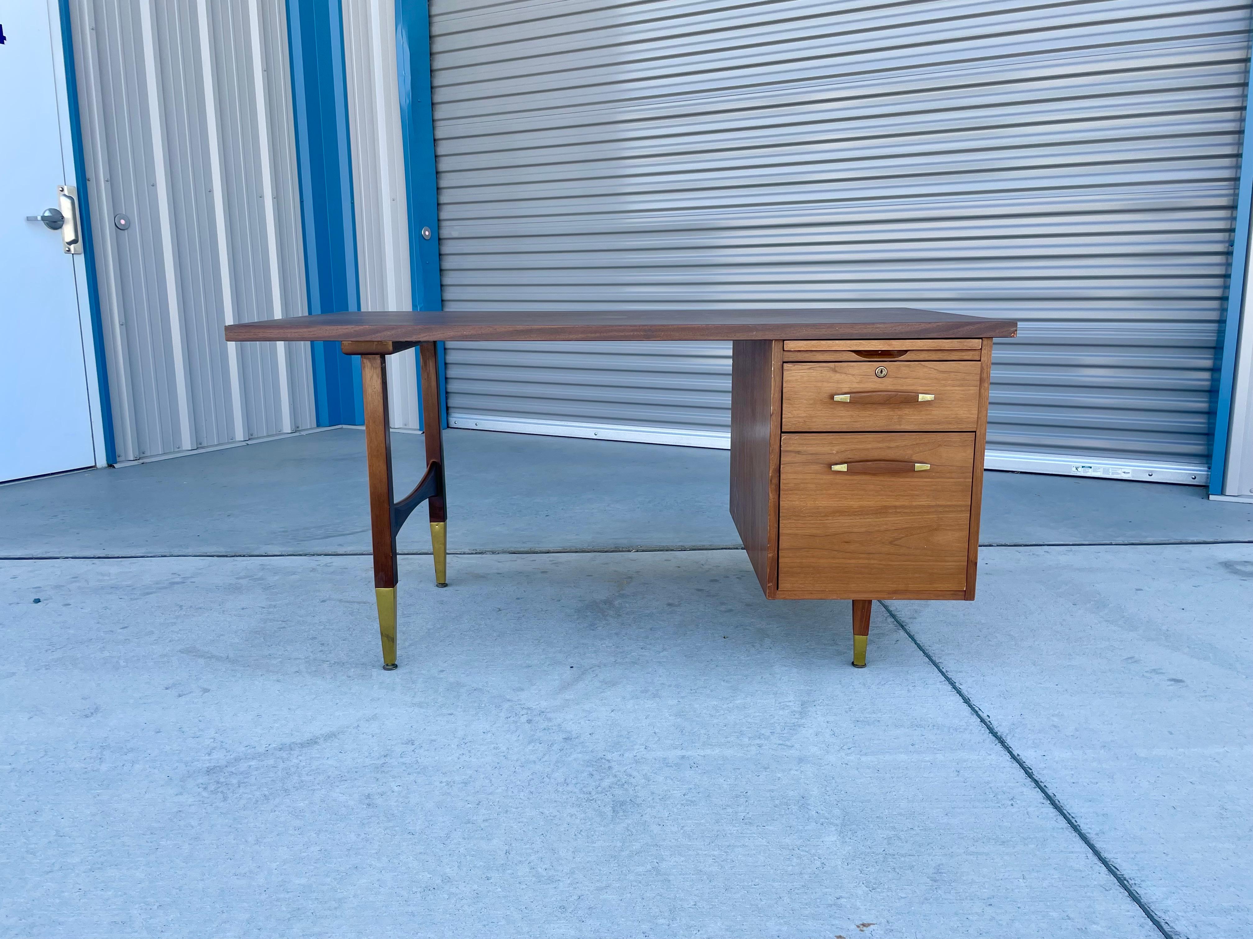 Mid-century walnut executive desk designed and manufactured in the United States circa 1960s. The desk is amazing and boasts a beautiful walnut frame with a sleek formica top. The desk also comes with a pull-out drawer and filling cabinet, offering