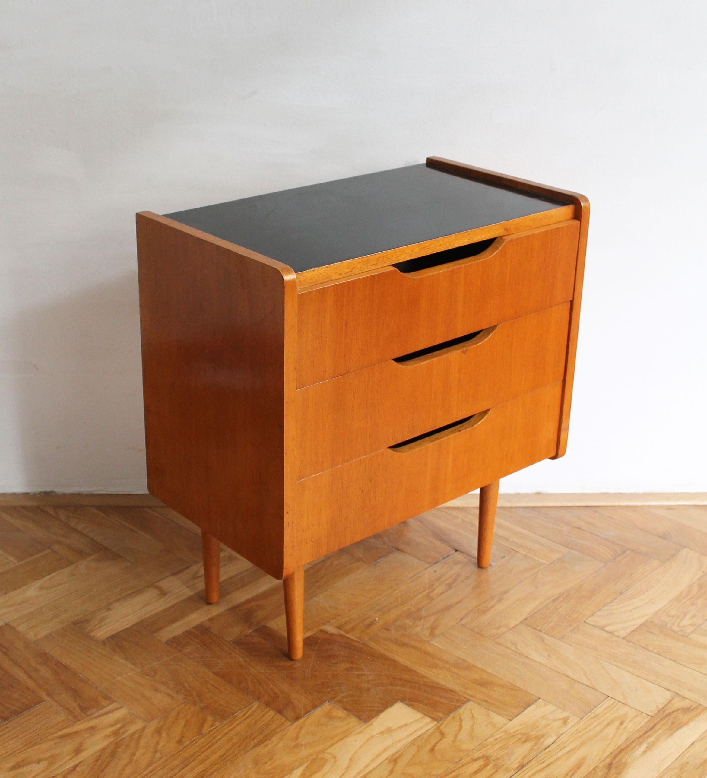 Dies ist ein original Mid Century Nachttisch, entworfen und hergestellt von Novy Domov in der ehemaligen Tschechoslowakei in den 1960er Jahren.

Die satte Farbe des Buchenholzes steht in schönem Kontrast zur schwarzen Platte. Der Nachttisch steht