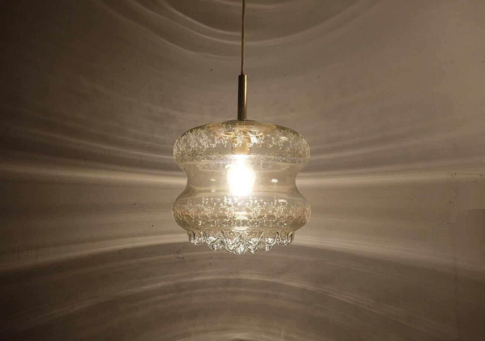 Beautiful 1960s 70s pendant light. The shade is made of slightly amber tinted glass with an etched pattern and a bubble surface at the bottom. Brass holder. White electric wire andwhite canopy. Holds one E27 bulb (bulb is not included in the offer).