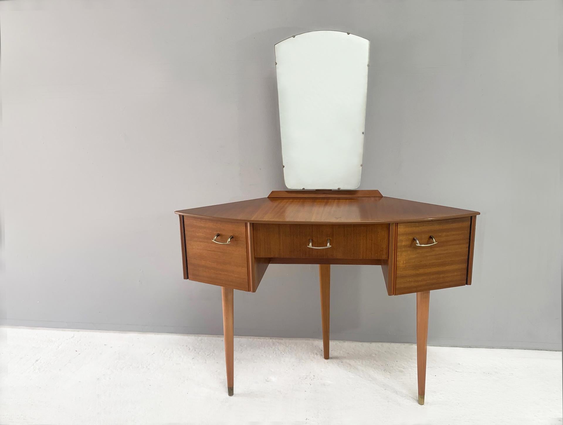 A very rare petite angular 3 leg dressing table by respected English maker Avalon. A distinctive V shape allows it to stand on just 3 legs. Walnut veneer throughout with brass handles and leg tips. Mirror is adjustable.

Size 
Overall height