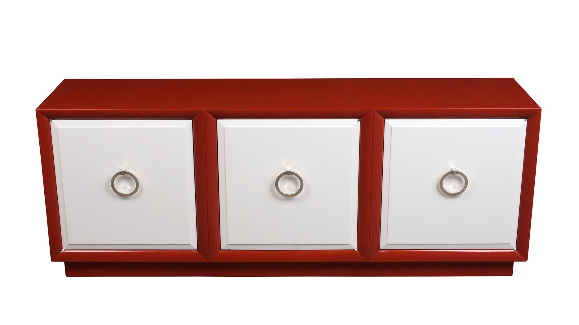 This elegant 3 door Mid-century credenza is stained in red and white color combination with a lacquer finish. This piece has three large doors with chrome round pull handles and an interior wood shelf for ample storage space and rests on a floating