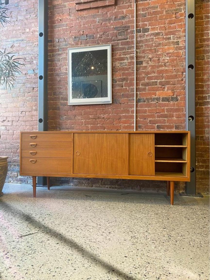 Presenting this exquisite mid century teak storage marvel hailing from the 1960s. Its two sliding doors conceal adjustable shelving, while on the left, a bank of drawers adorned with stunning pulls awaits. Meticulously restored by our skilled team,