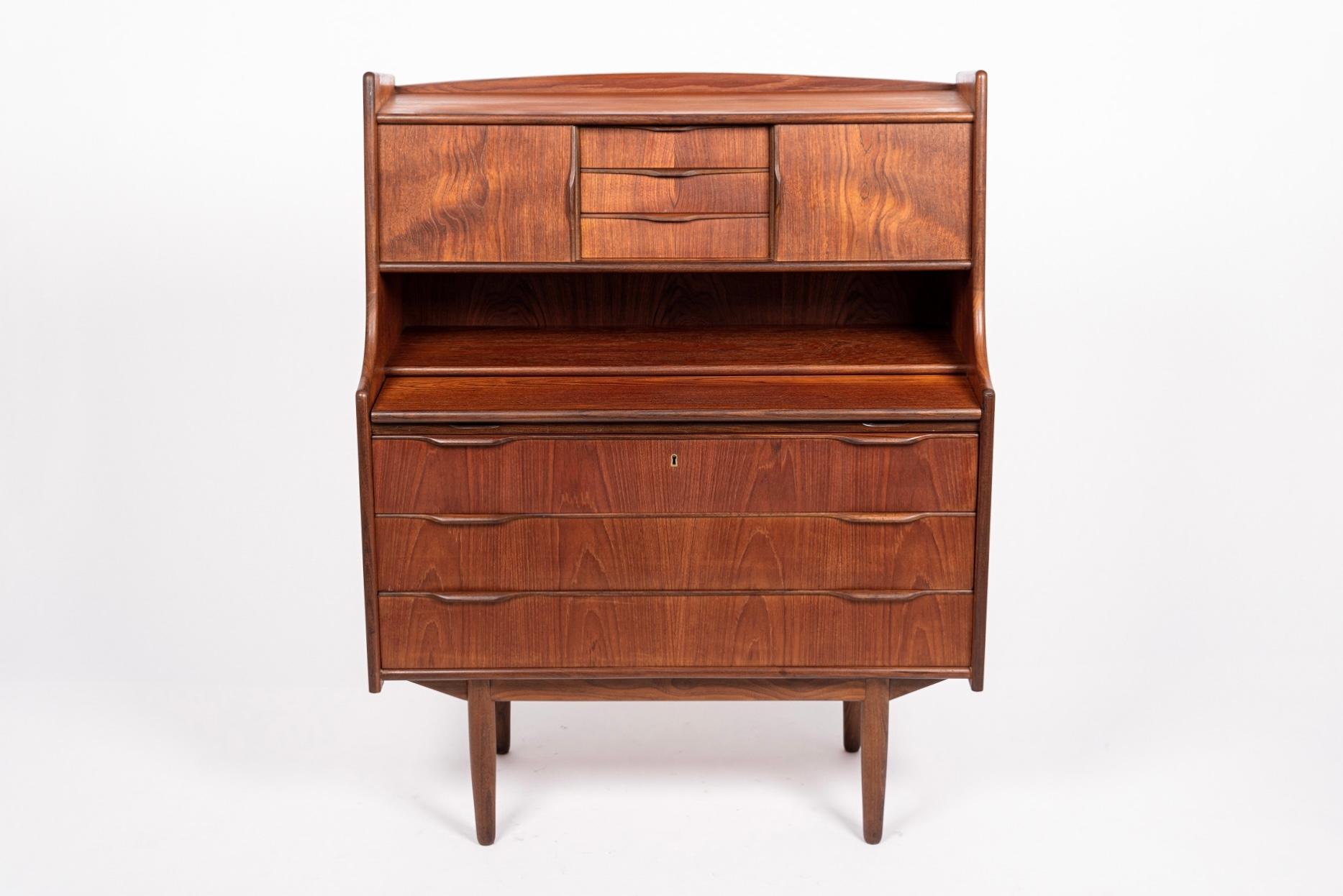 This vintage midcentury Finnish modern teak secretary desk cabinet was made in Finland by Venesta circa 1960. The Classic Nordic modern design has clean, Minimalist lines and gentle curves and the teak exhibits beautiful natural grain. The upper