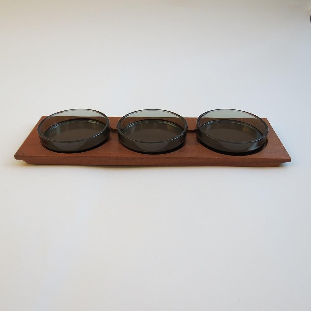 Very nice quality nibbles dish by Decor Woodware, England
Teak tray with cut out slots for 3 round smoked glass dishes. 
stamped to the underside Decor Woodware, English made
Dates from the 1960s
In good condition
41cm 13cm 2cm Each bowl measures