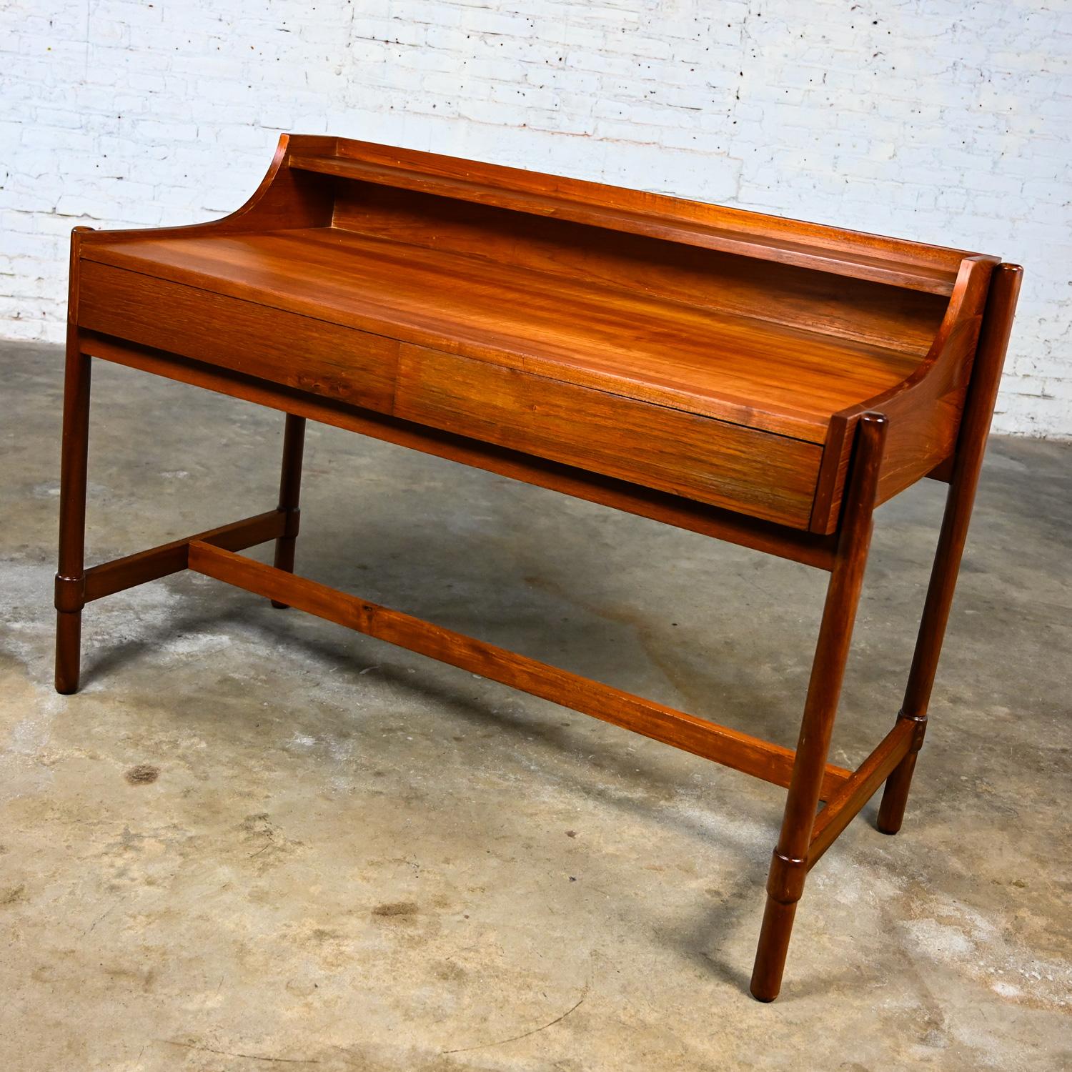 Handsome vintage mid-century modern or Scandinavian Modern teak writing desk with raised back shelf, 2 drawers, and straight round legs, made in Bangkok. Beautiful condition, keeping in mind that this is vintage and not new so will have signs of use