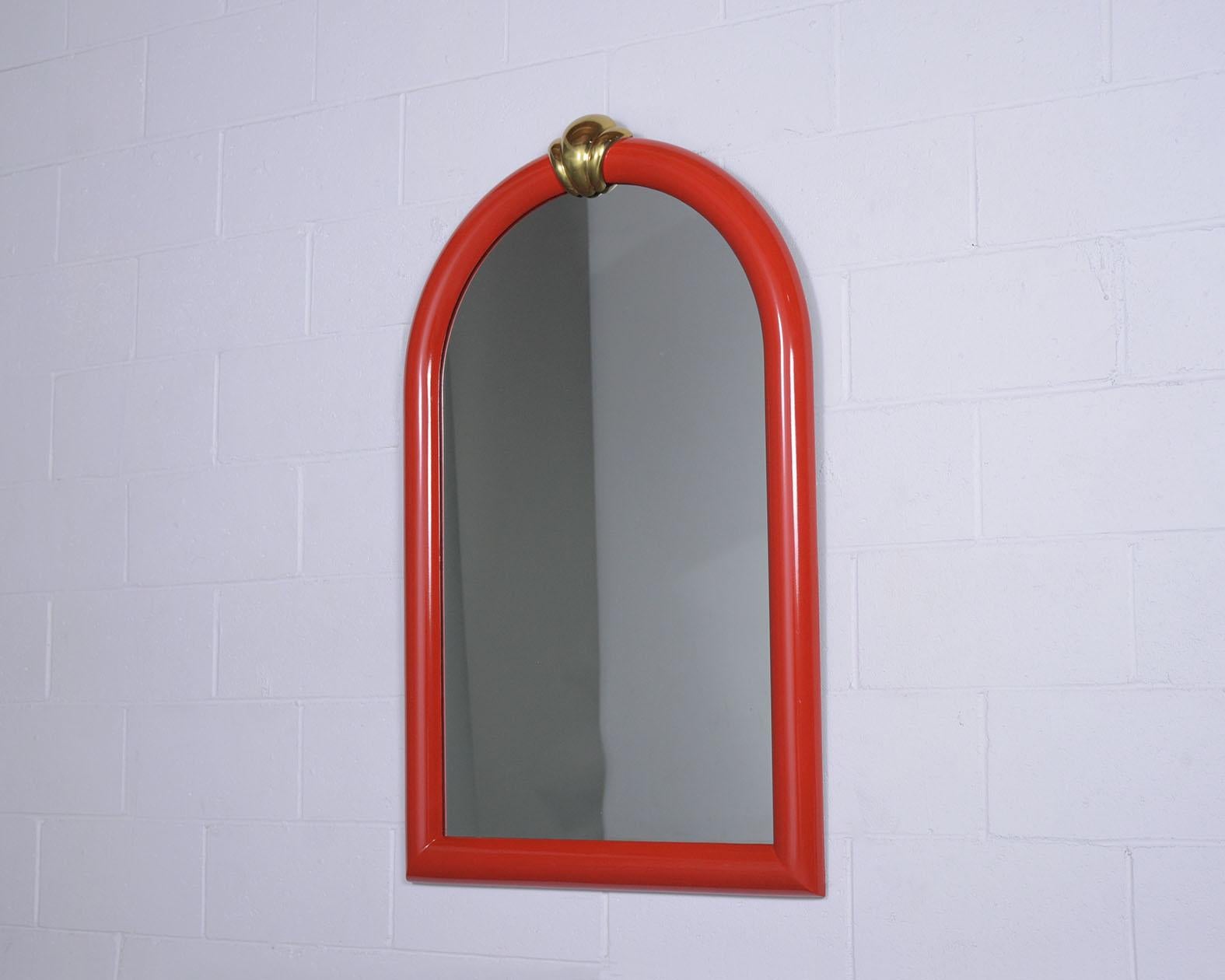 An extraordinary vintage wall mirror is made out of wood and has been completely restored by our team of expert craftsmen. The mirror features a deep red color with a lacquered finished 4' height frame arched design with the elegant solid shell